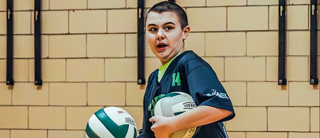 student holding volleyballs