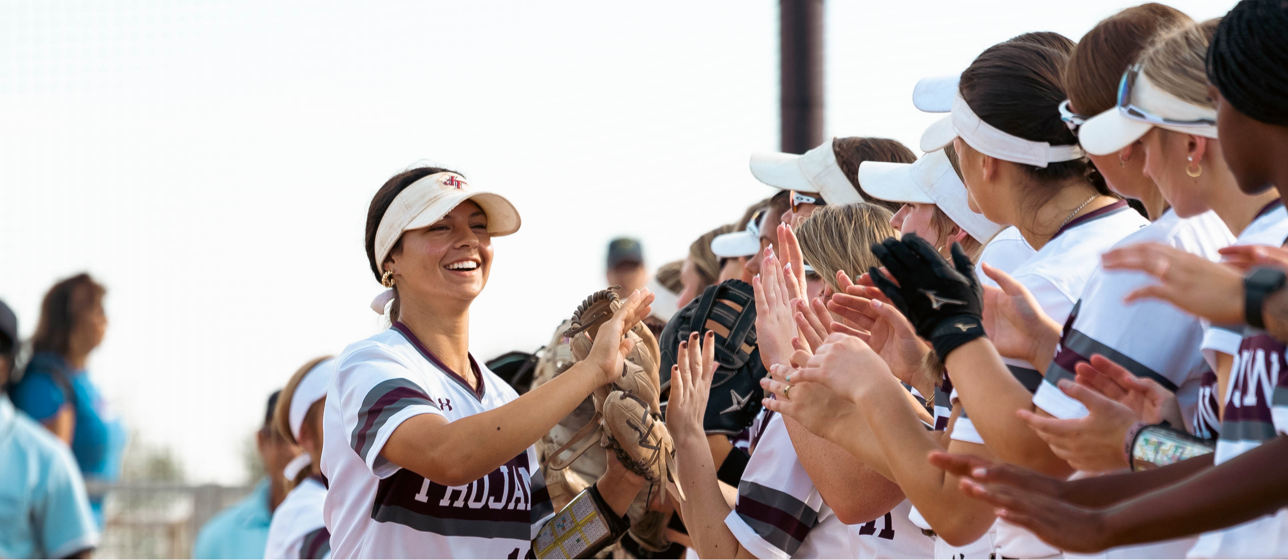 Softball player smiling and high fiving her teammates