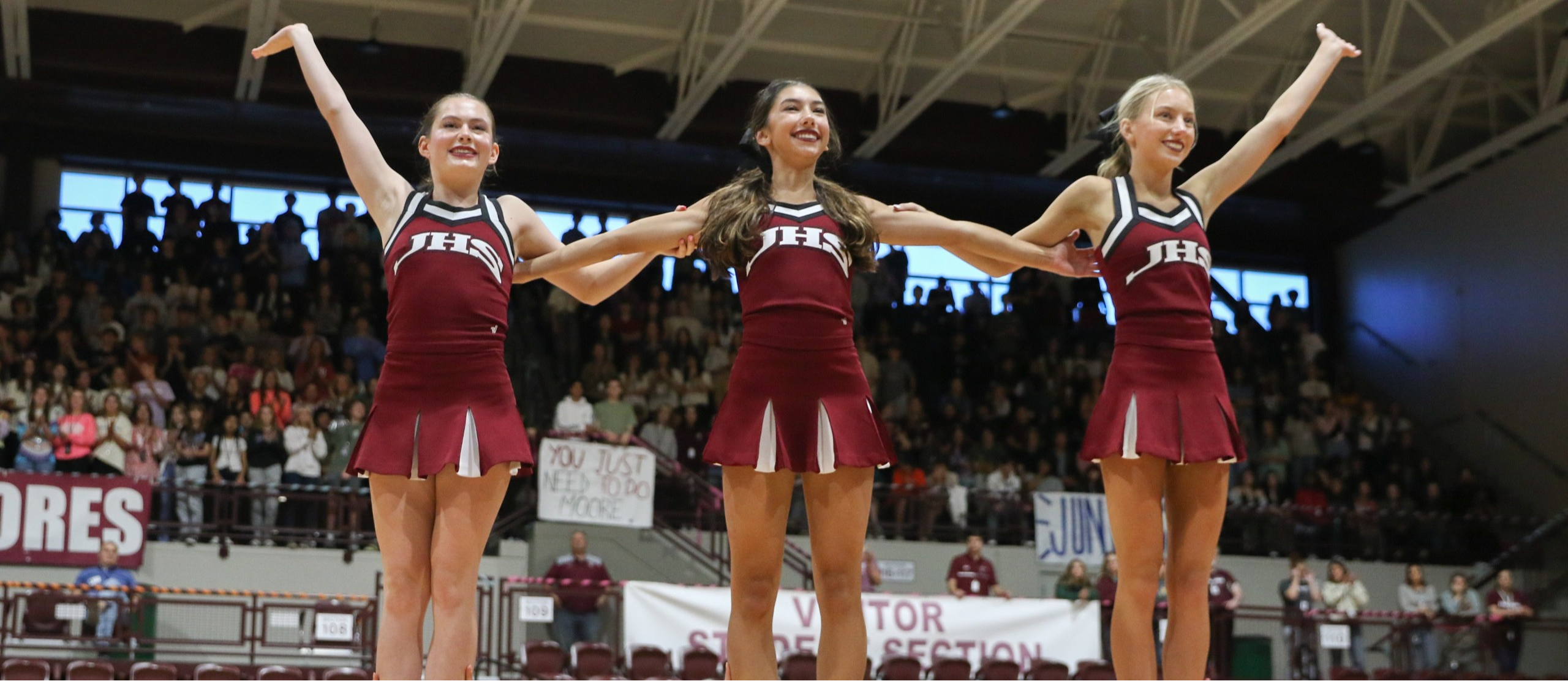 3 cheerleaders standing in front of auditorium