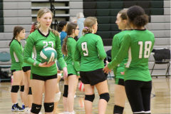 team standing around, one girl has volleyball