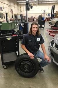 Student posing for picture with tire