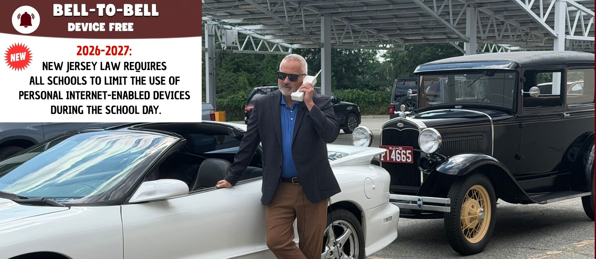A man in a suit stands next to a white sports car. Behind him is a black vintage car.