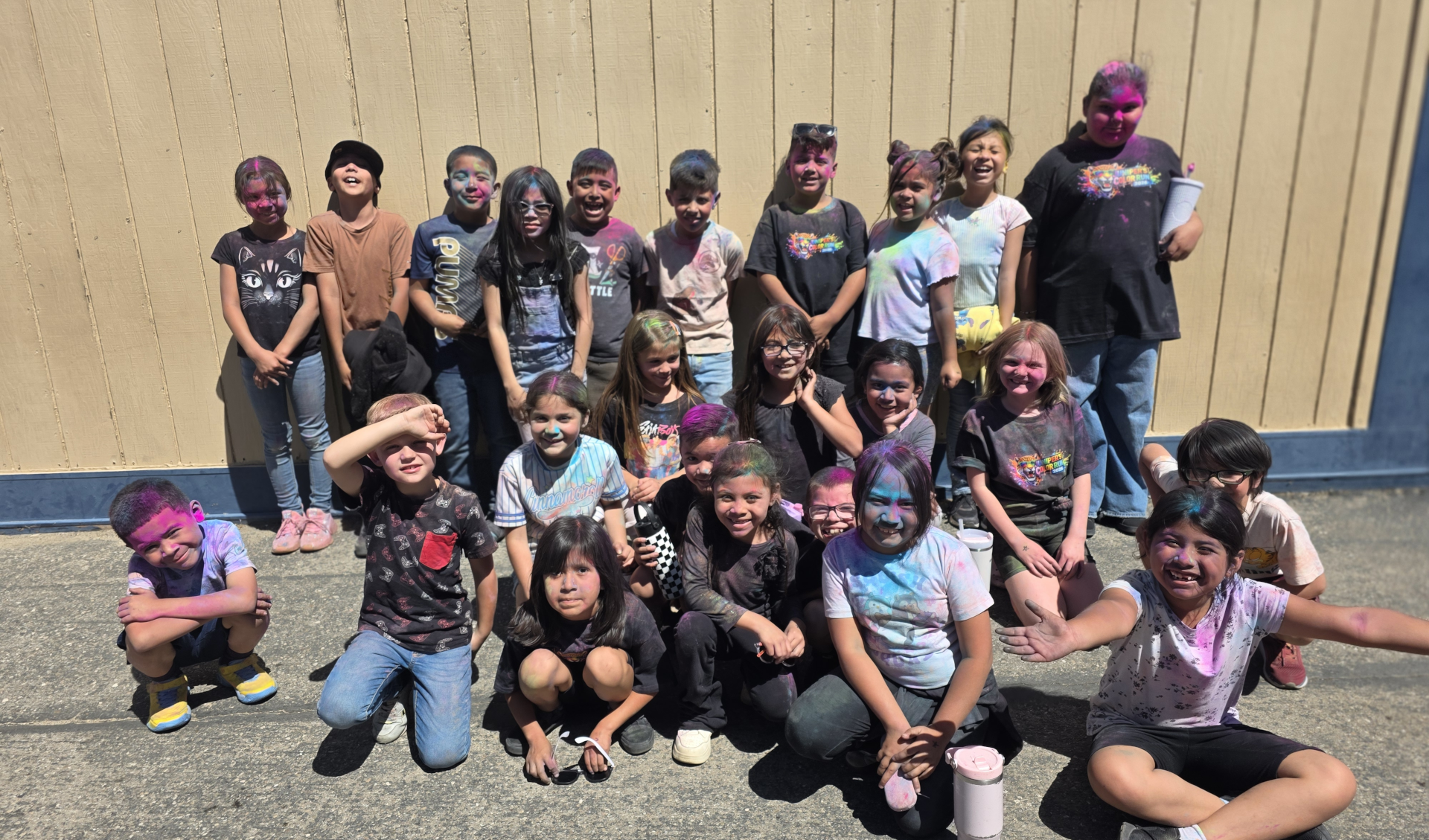 Ms. Phillip's first grade class standing in front of a portable with colored chalk on their faces.