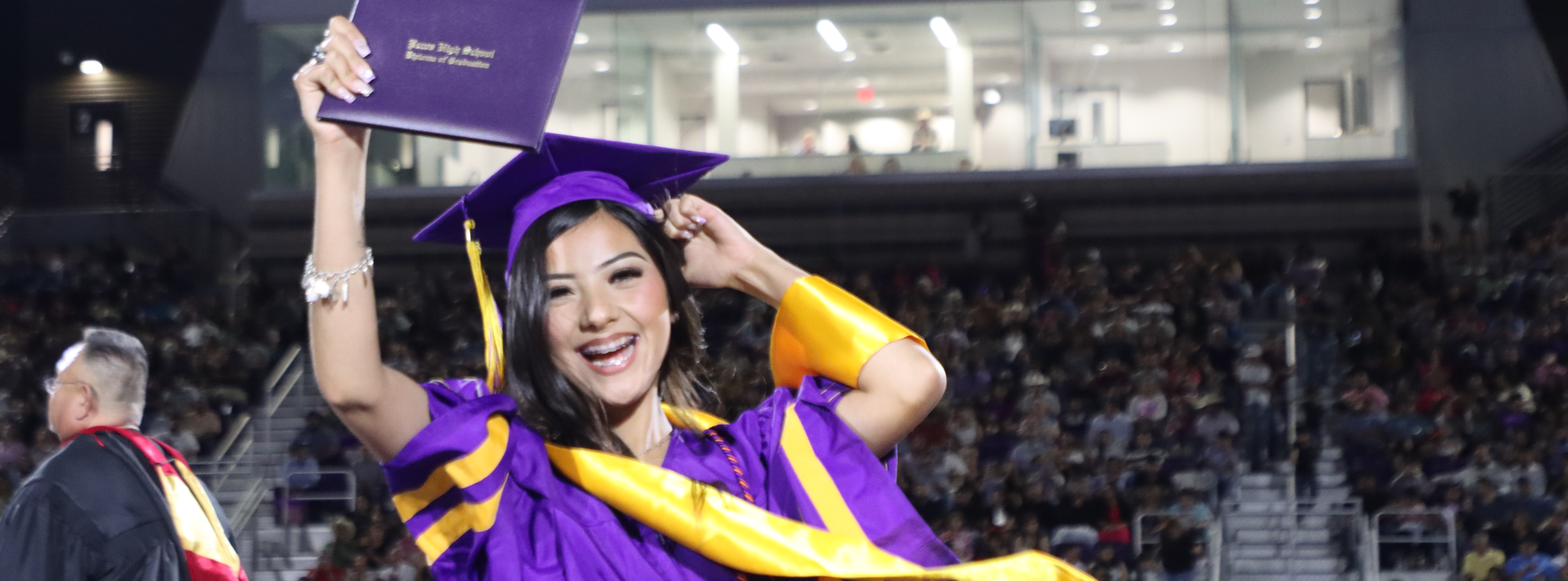 graduate holding diploma in the air and smiling