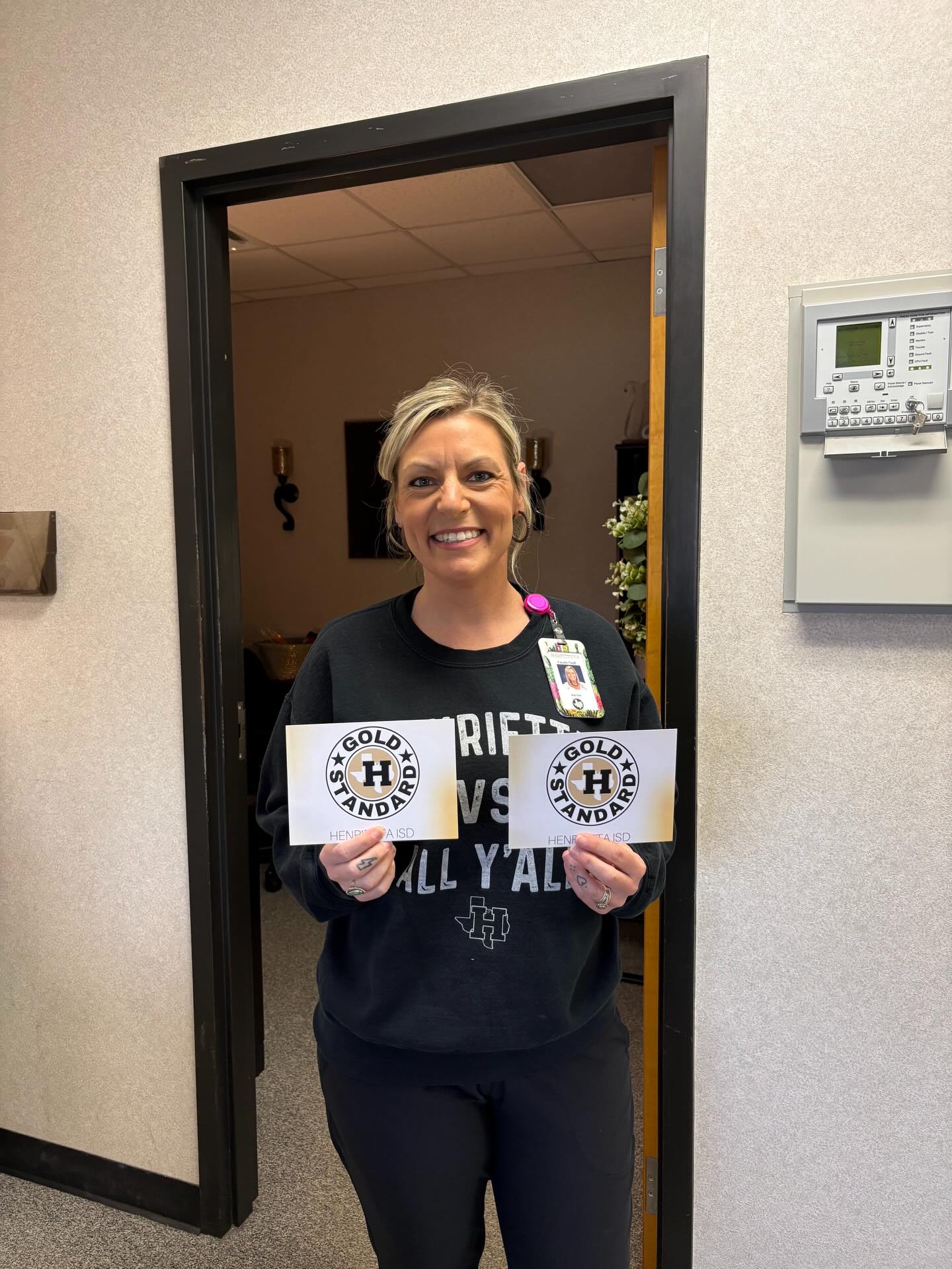 Woman with ID badge stands in doorway of building, holding up two signs. One reads "RIGHT VS ALL YAL."