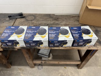 Four blue boxes with yellow and black images on top of a wooden table. A box is partially visible behind the table.