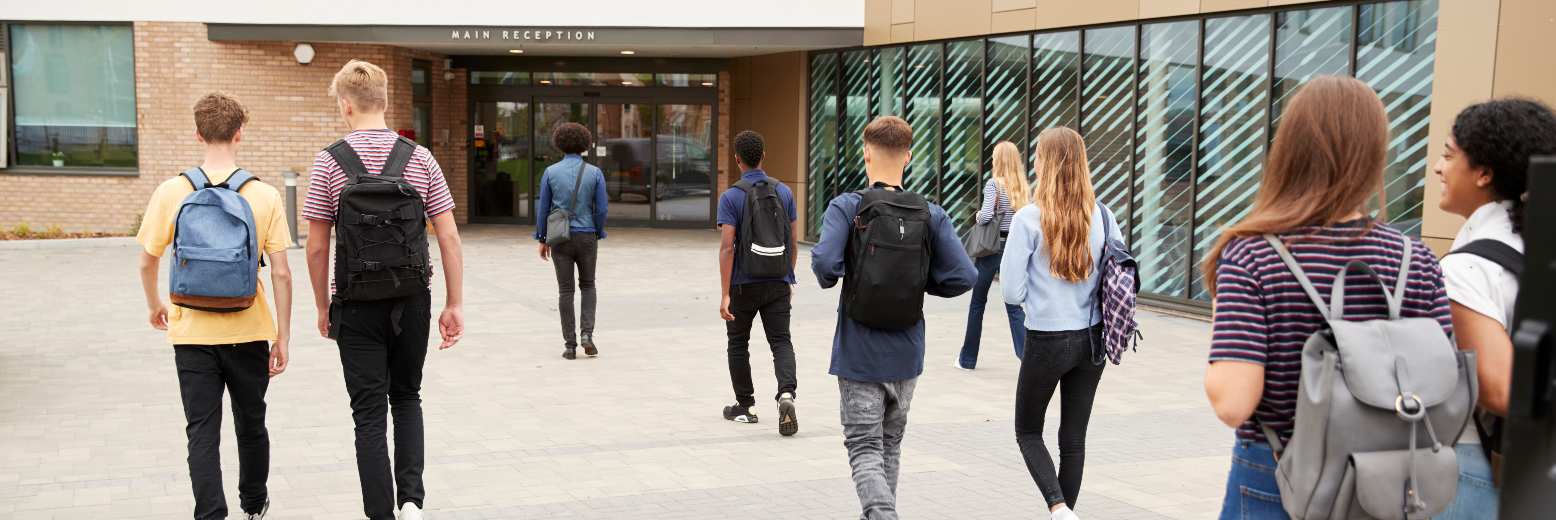 Several students walking towards the entrance of a school