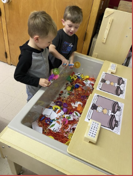 two preschool aged boys playing with blocks at a desk in school