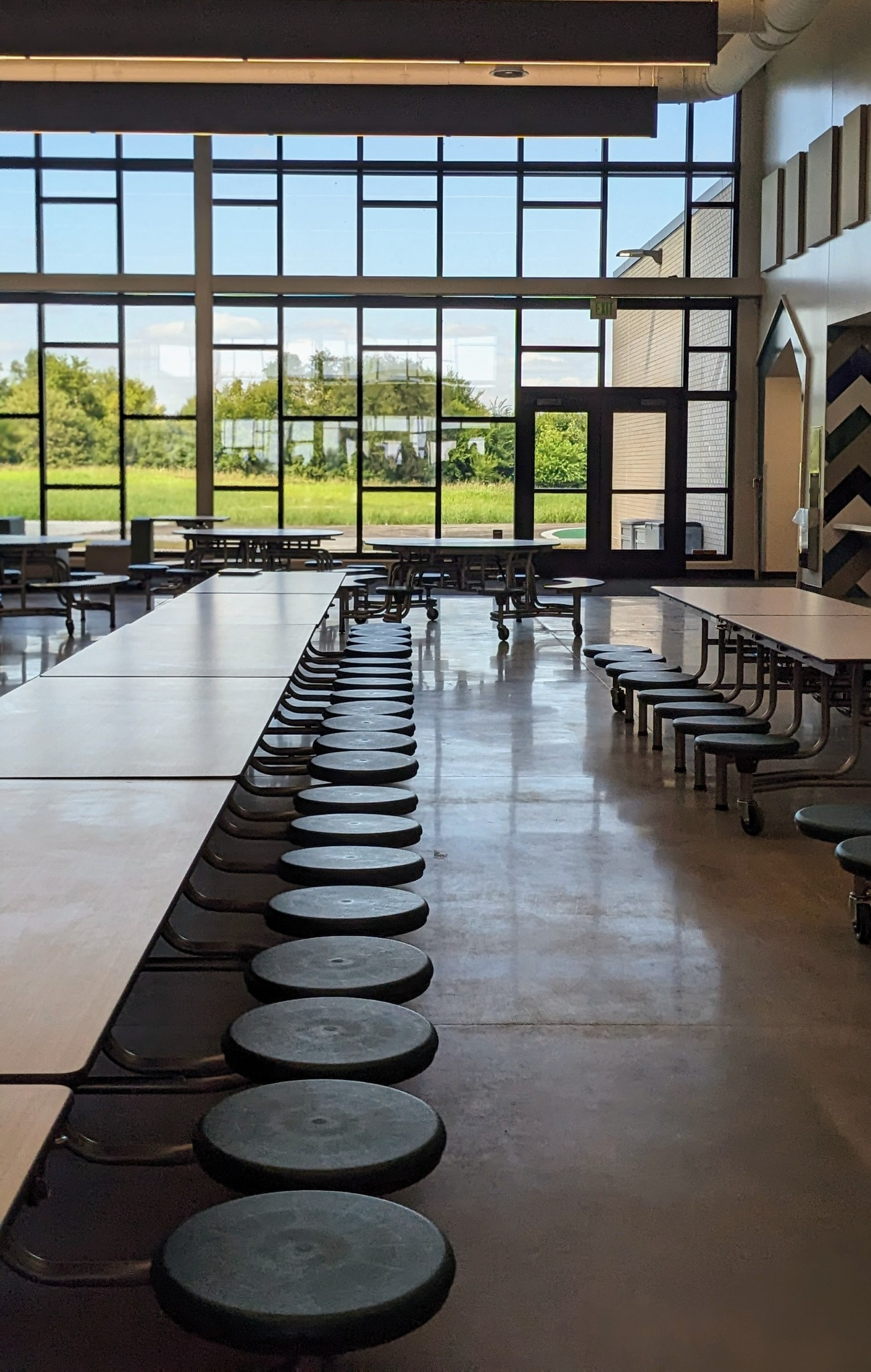 Boone CSD - Commons showing open light with all the windows and tables and stools