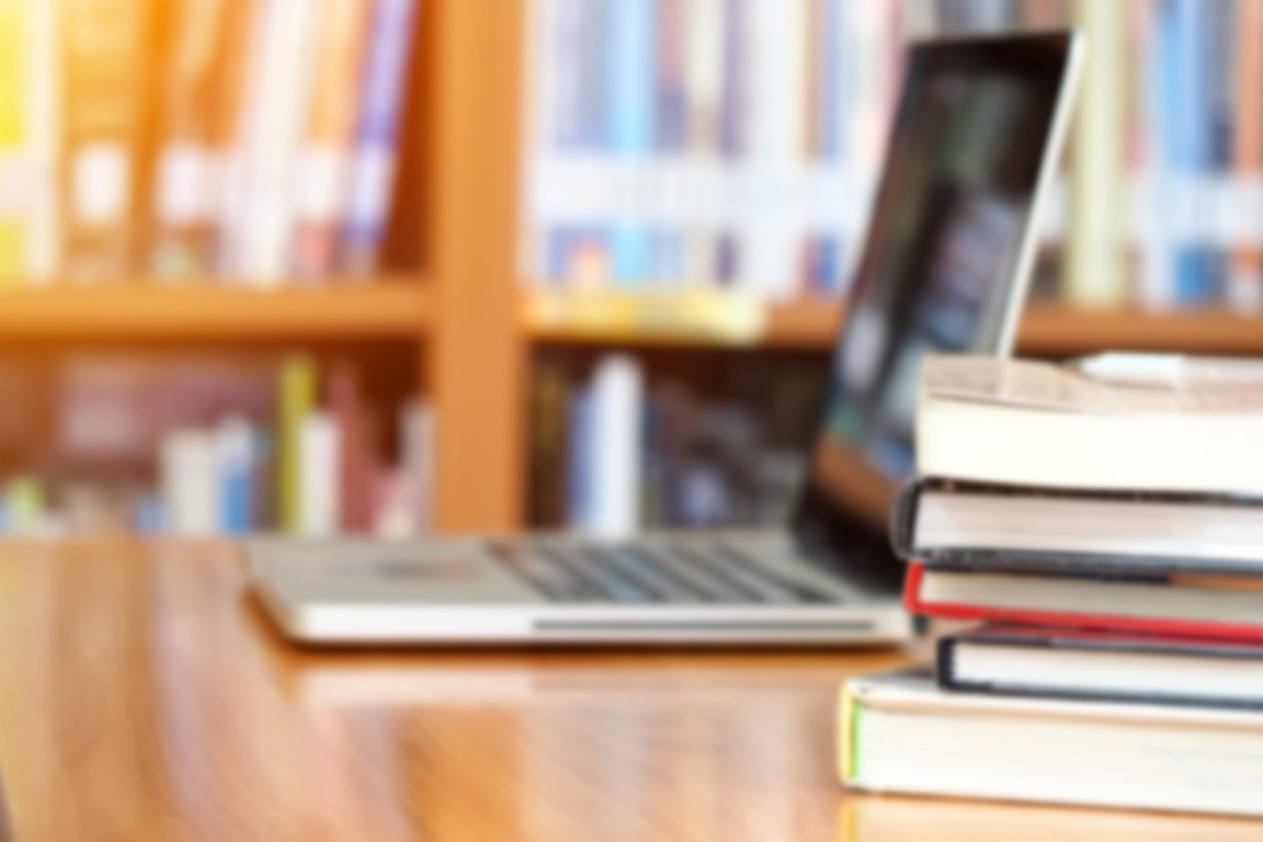 image of computer and books in a library