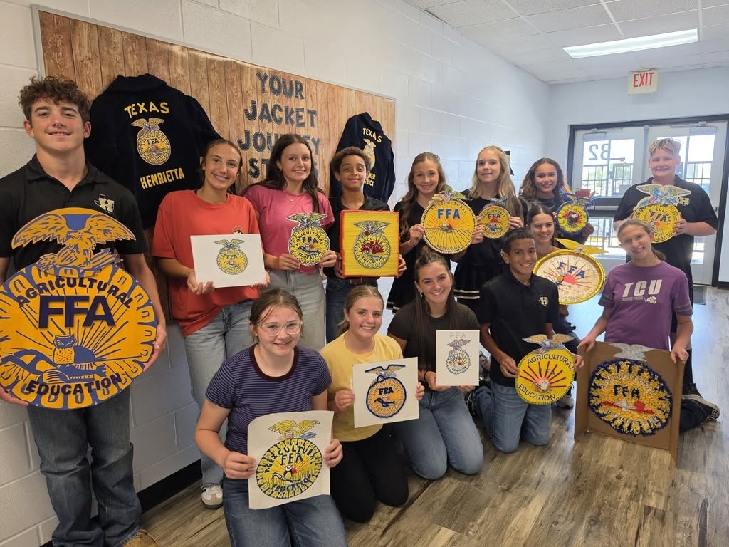 Group of students and instructors in a room, holding signs, smiling, and posing for a photo.
