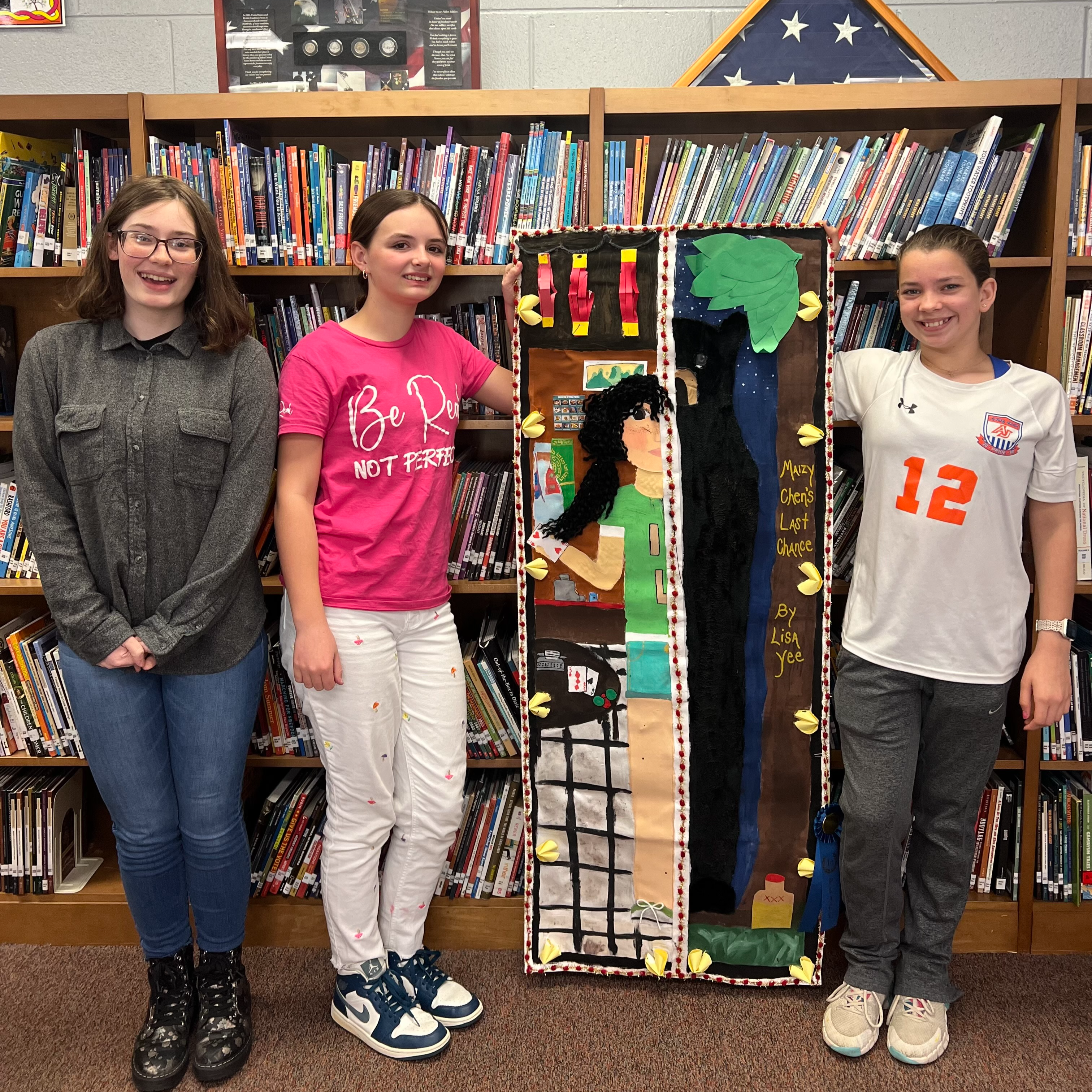 picture of winning banner with student participants standing in front of book shelf