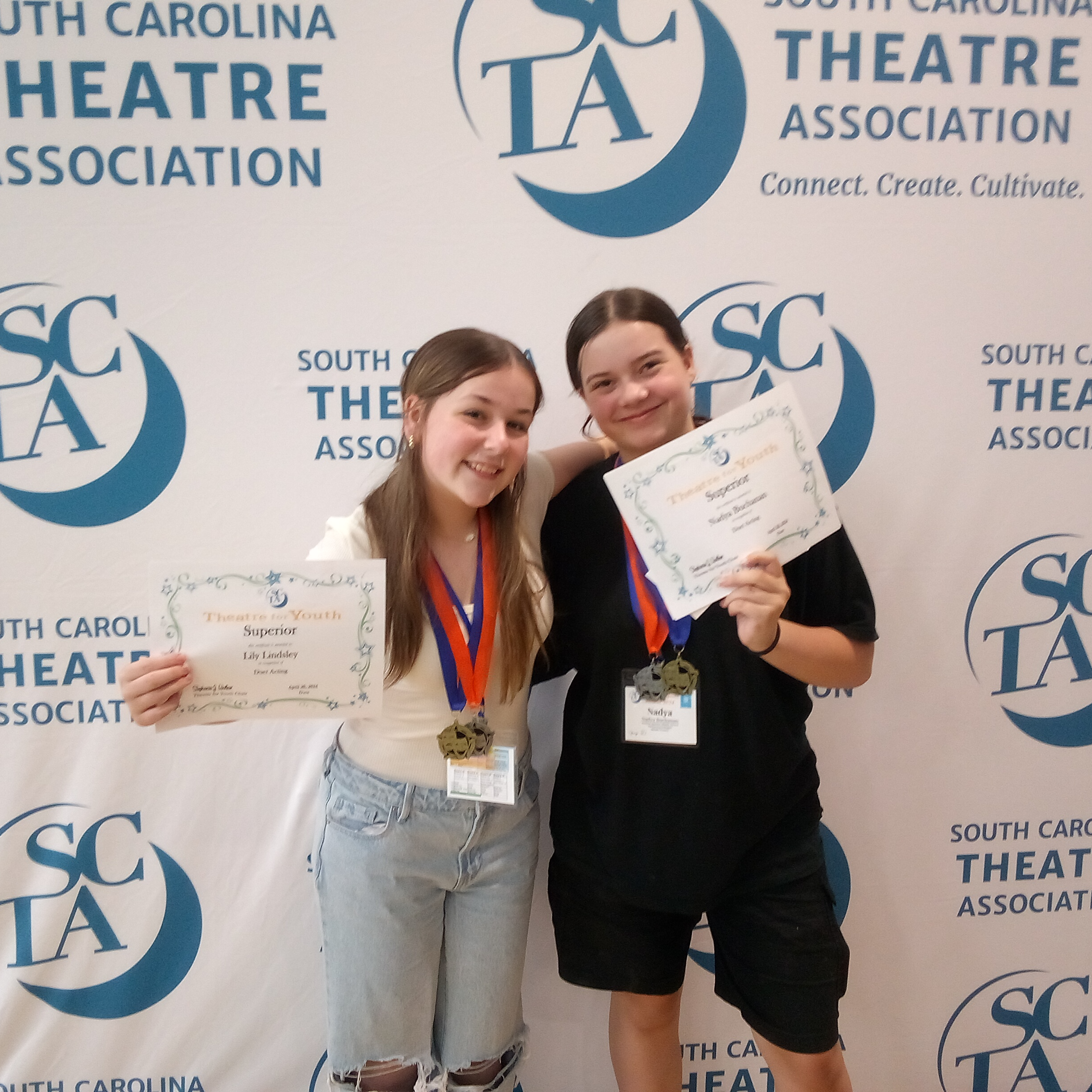SC Theatre Association backdrop with students holding superior certificates