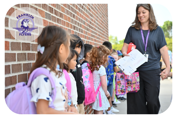 franklin teacher walking around her students lined up against the wall of the building ready to go inside to their classroom.