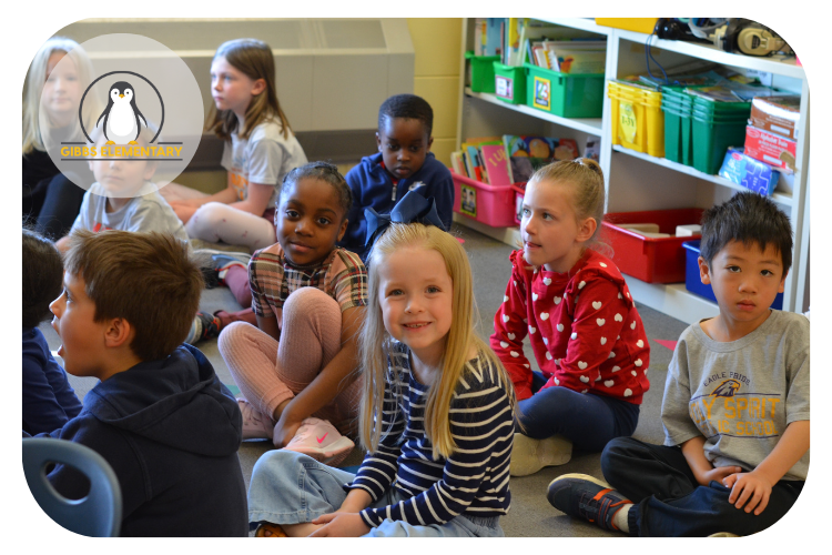 Gibbs students sitting of the floor of the classroom smiling at the camera.