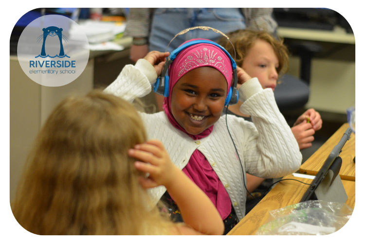 riverside students working together on iPad classroom activities with one student smiling at the camera while she puts her headphones on.