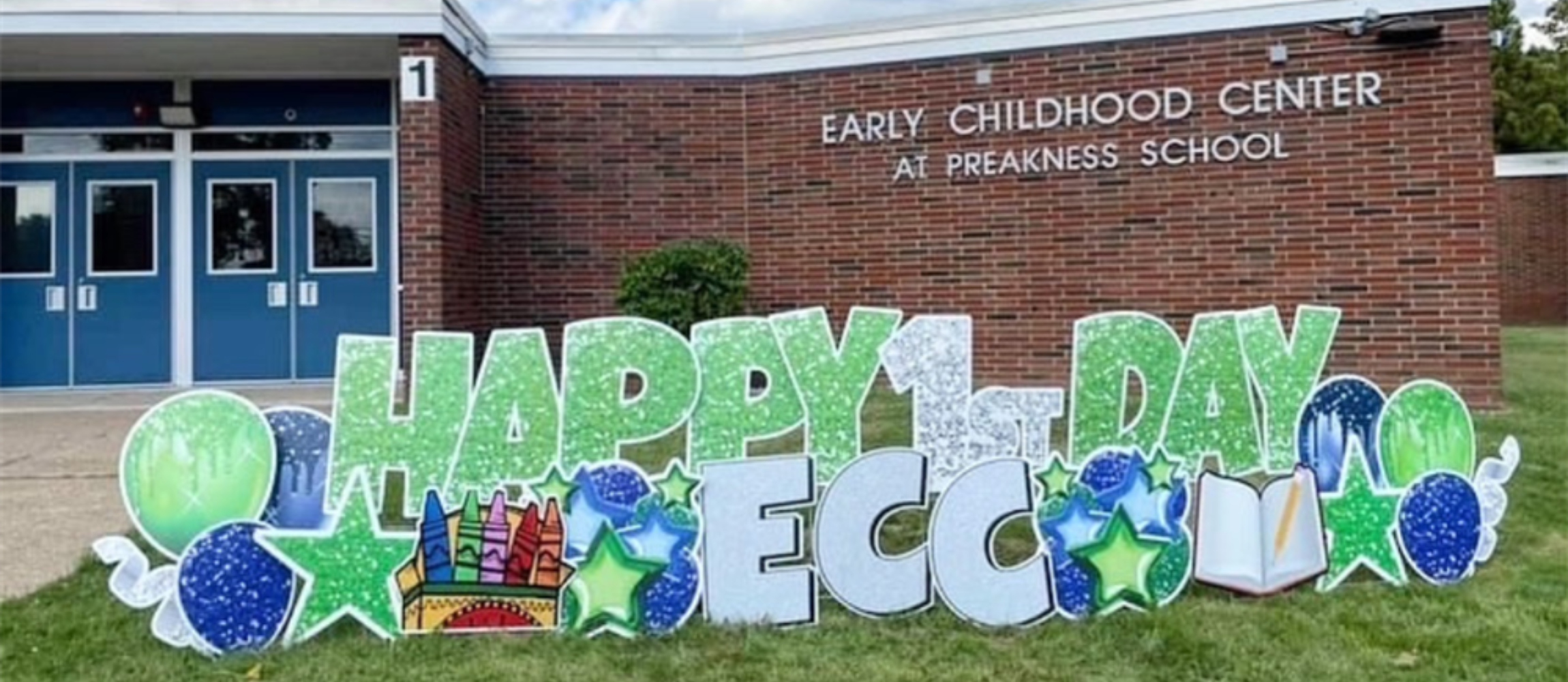 happy first day ECC sign hanging up outside of the school building