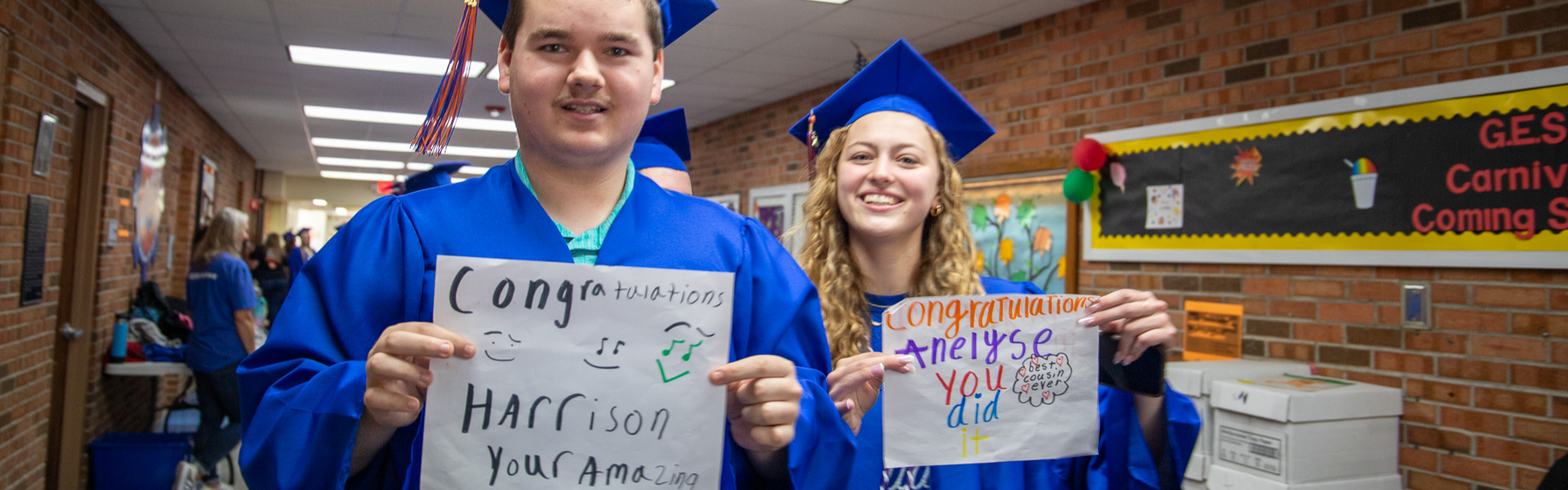 image of students in cap and gown holding signs