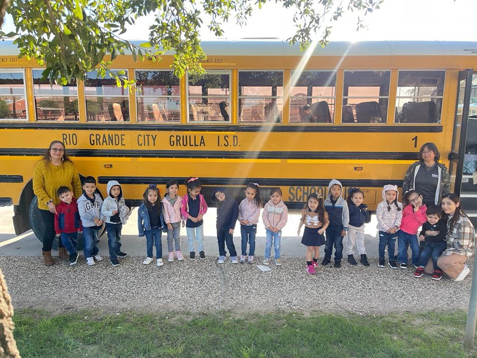 Students and staff posing in front of a school bus