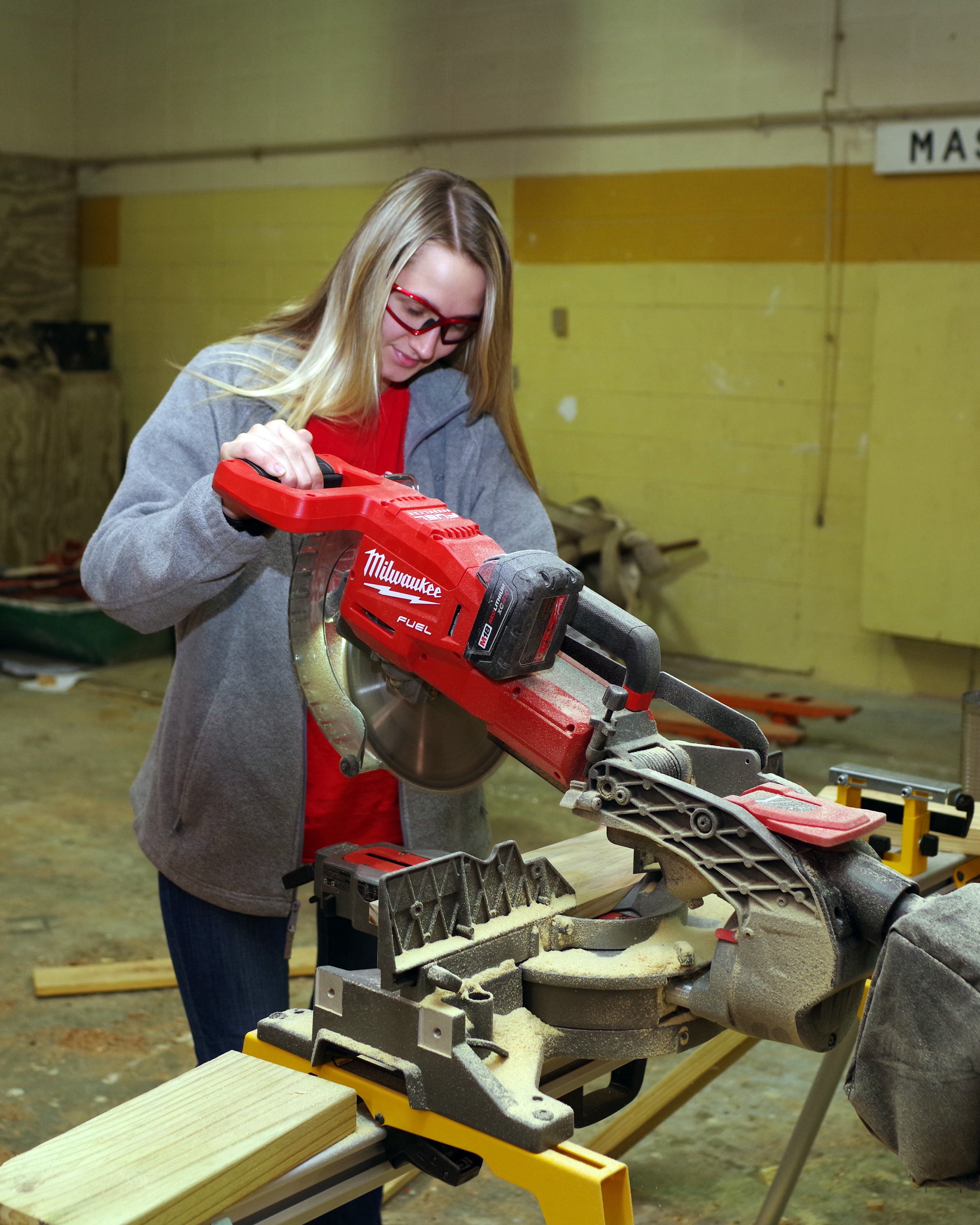 A Female student using a milwaukee Miter Saw