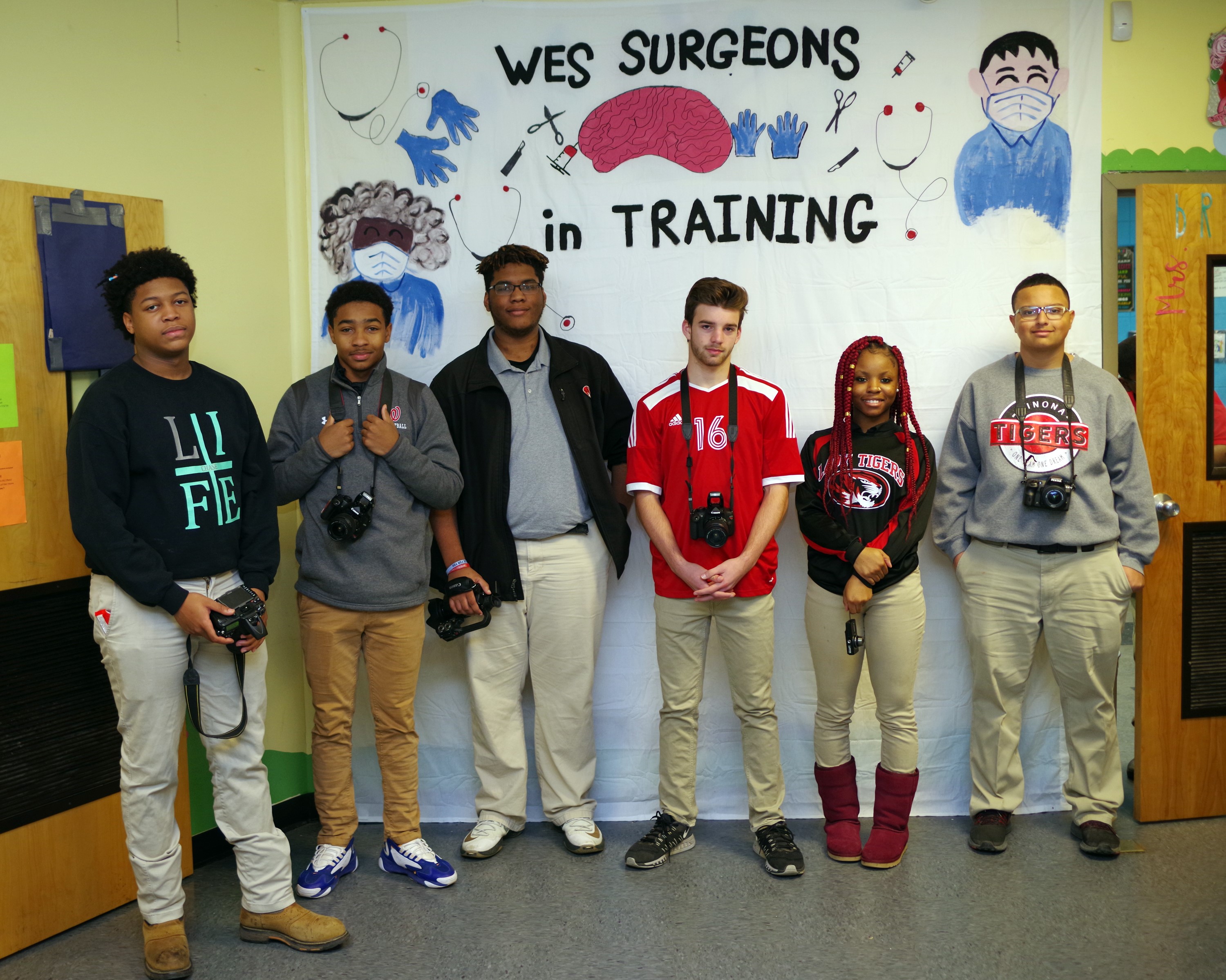 A group of 6 students standing in front of a wall that has Wes Surgeons in training written behind them.