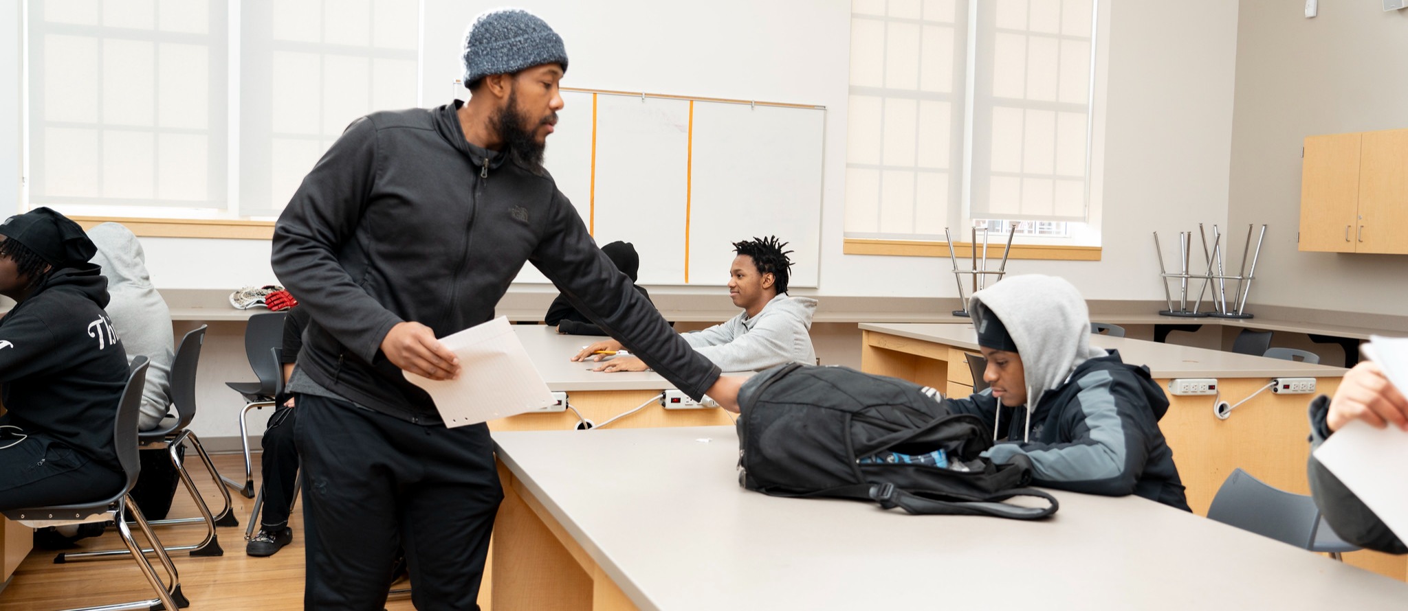 Staff member reaches out to get an assignment from a student at his desk