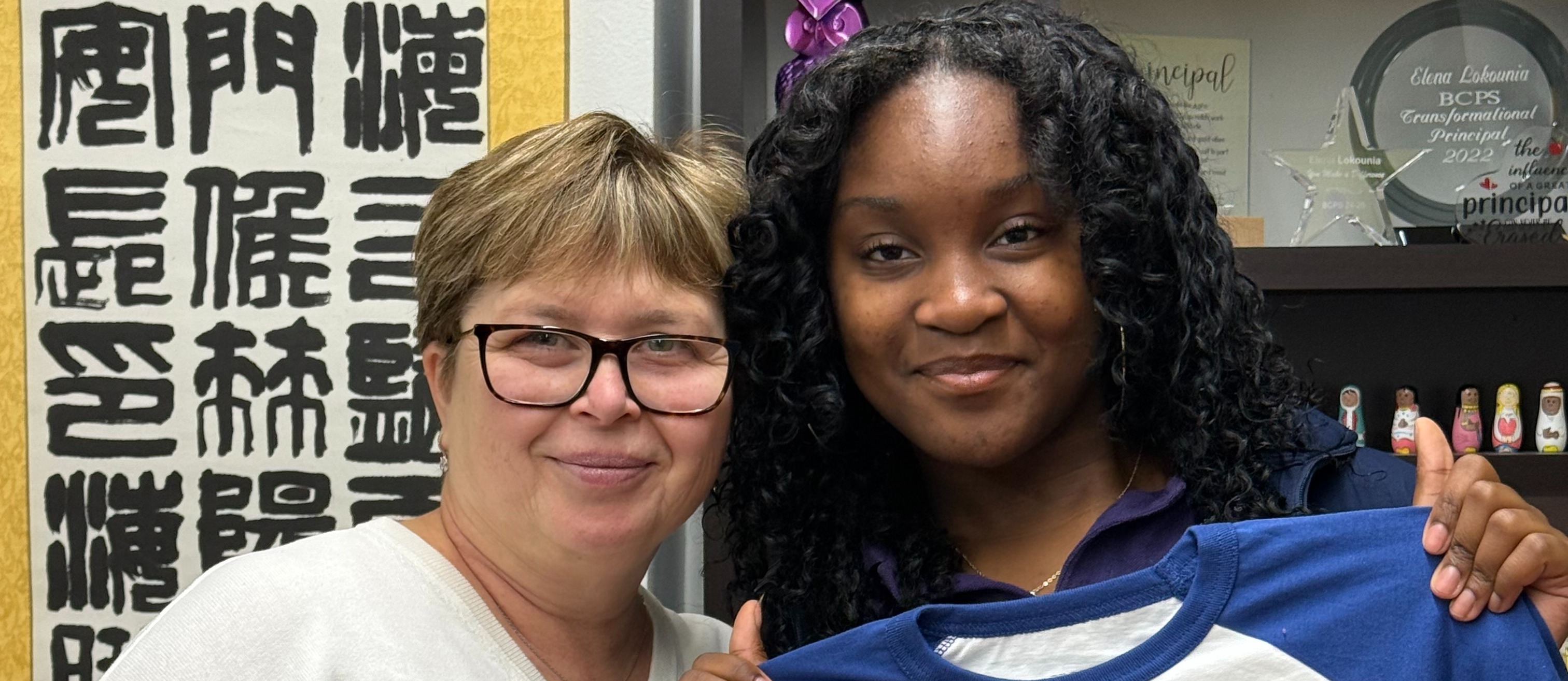 Teacher and student pose for a photo and smile
