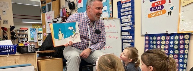 Superintendent Cyr reads a Dr. Seuss Book to a seated group of PreK students