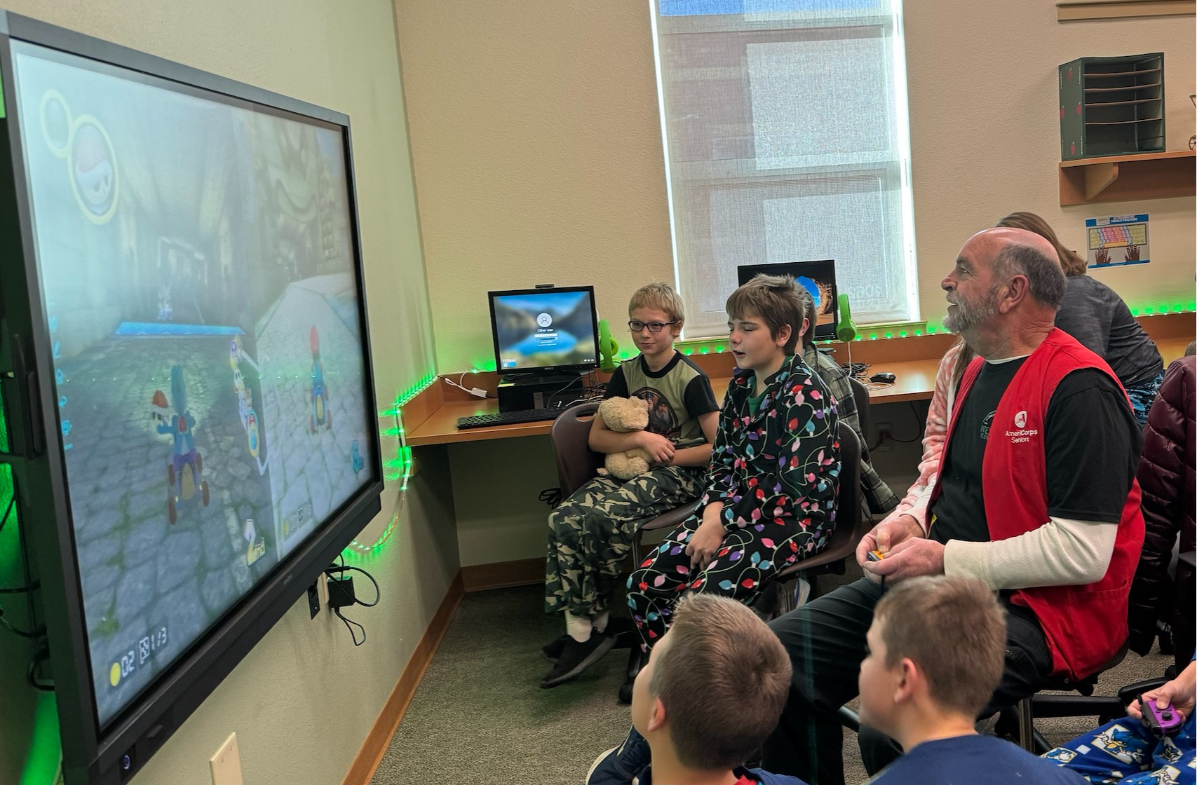 Foster Grandparent Hoyt, playing video game with students