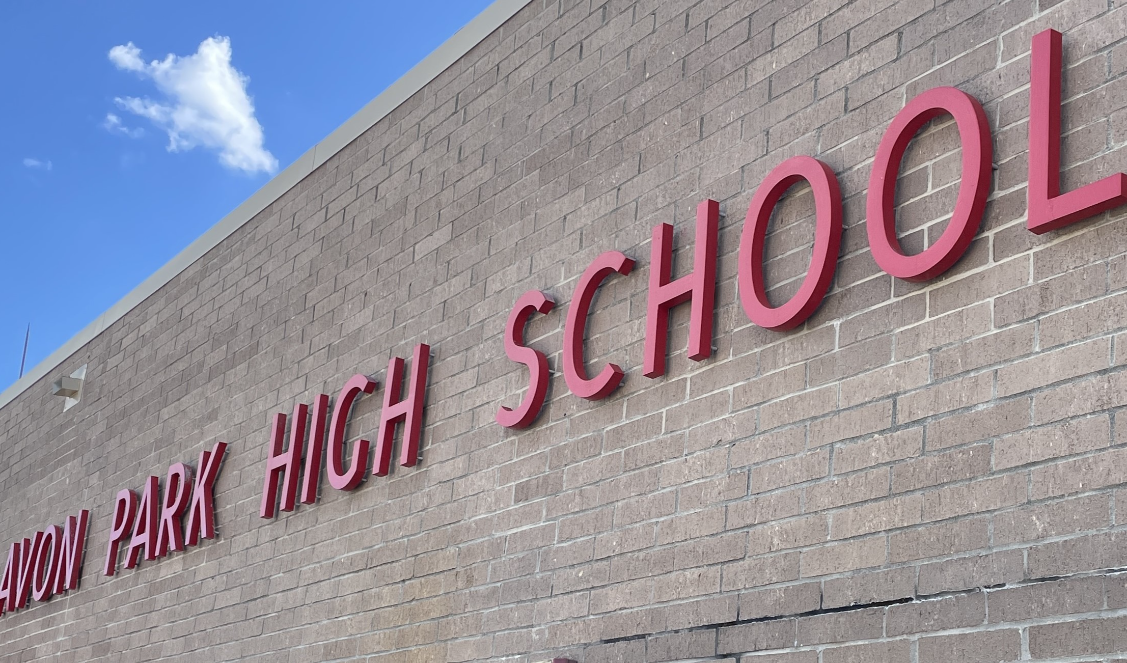 Red letters spelling 'AVON PARK HIGH SCHOOL' mounted on the exterior brick wall of the building.