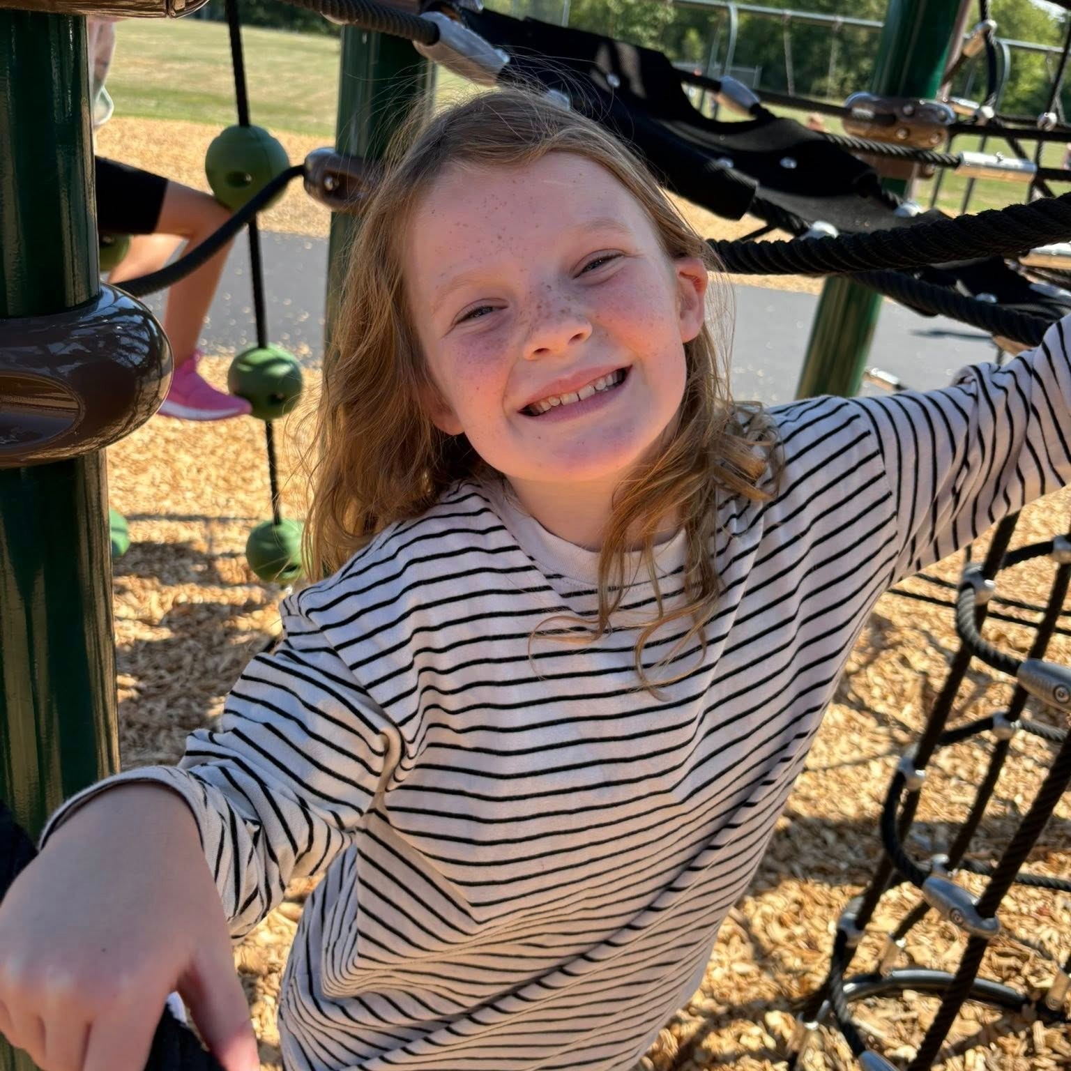 Addi smiling while playing on the playground