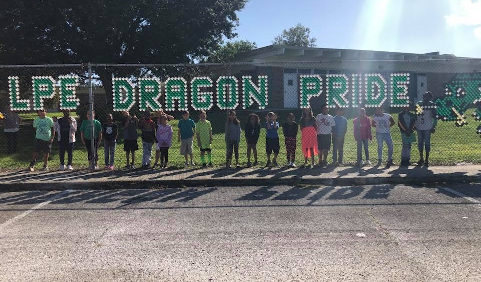 LPE Dragon Pride on fence with children standing by the fence.