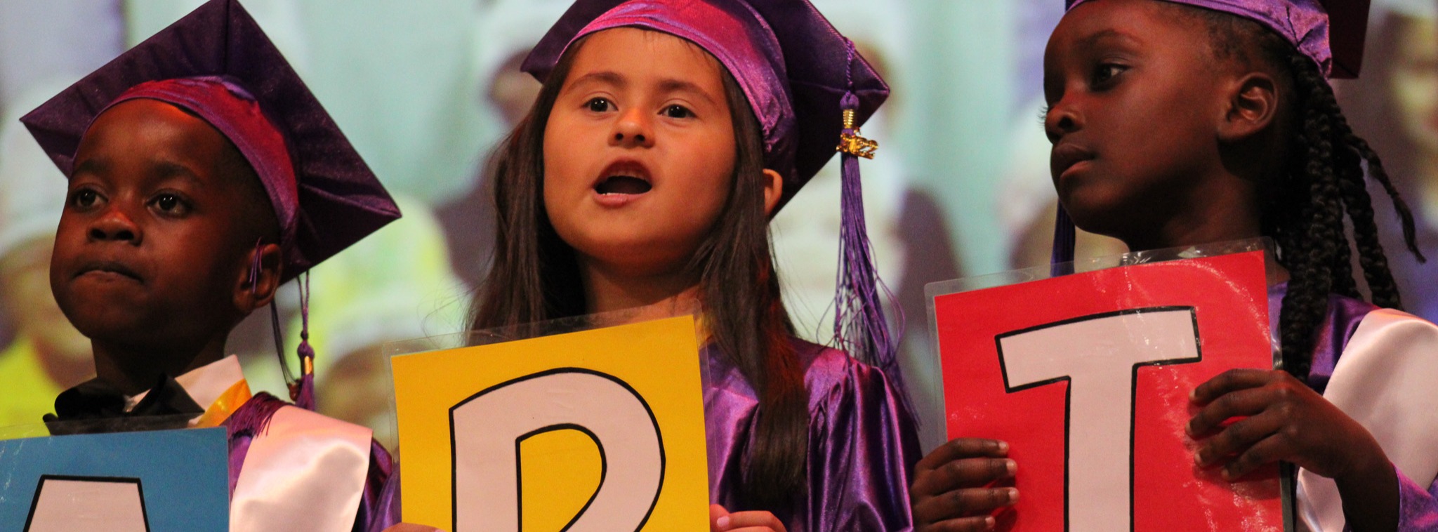 students in cap and gown holding up letters  A R T