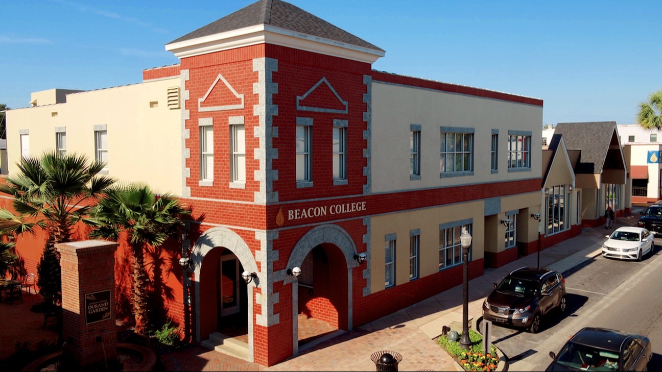 A red and white building with a gray roof. Cars are parked on the street.
