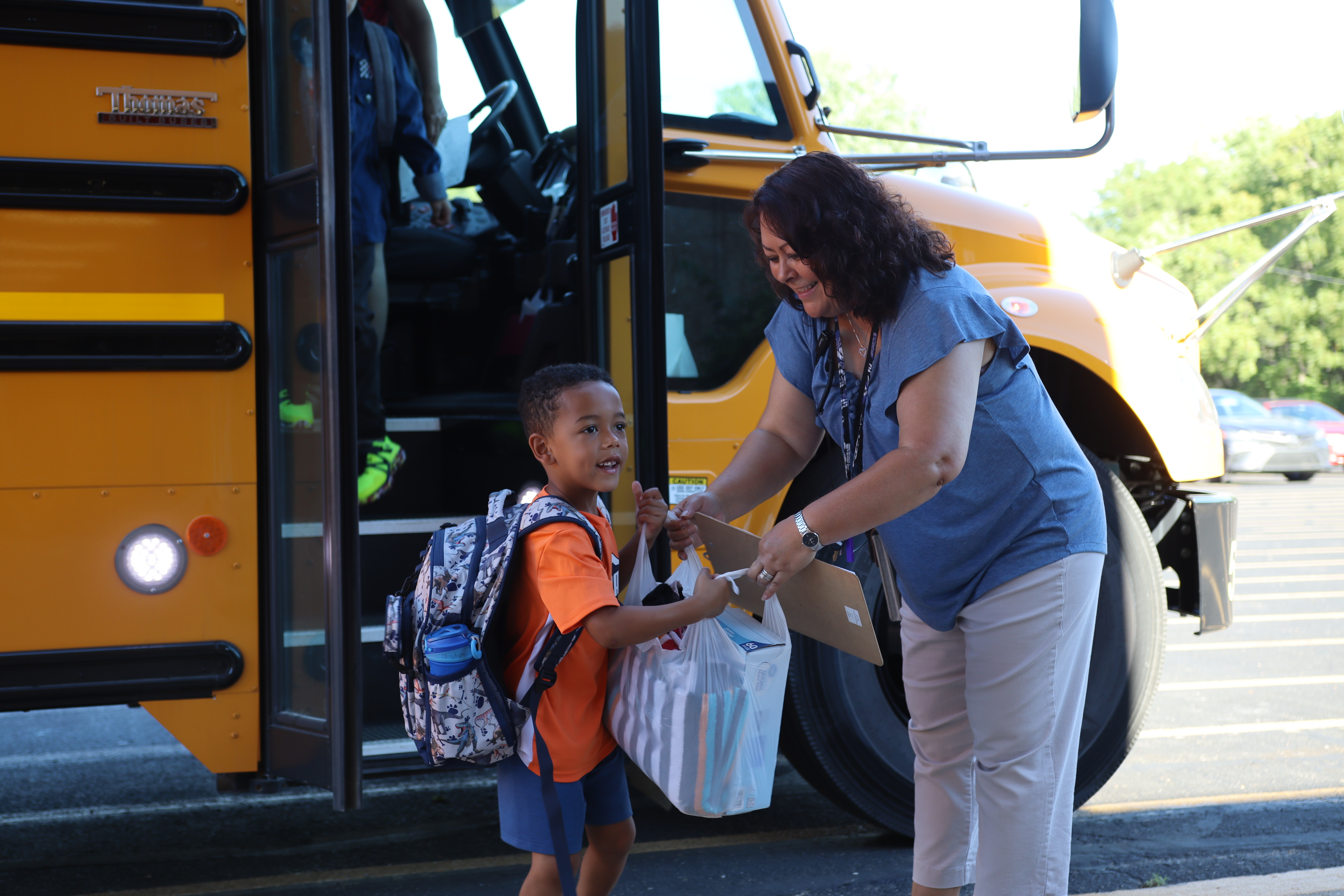 Dean of Students, Mrs. Hayes, helping a student off the bus.