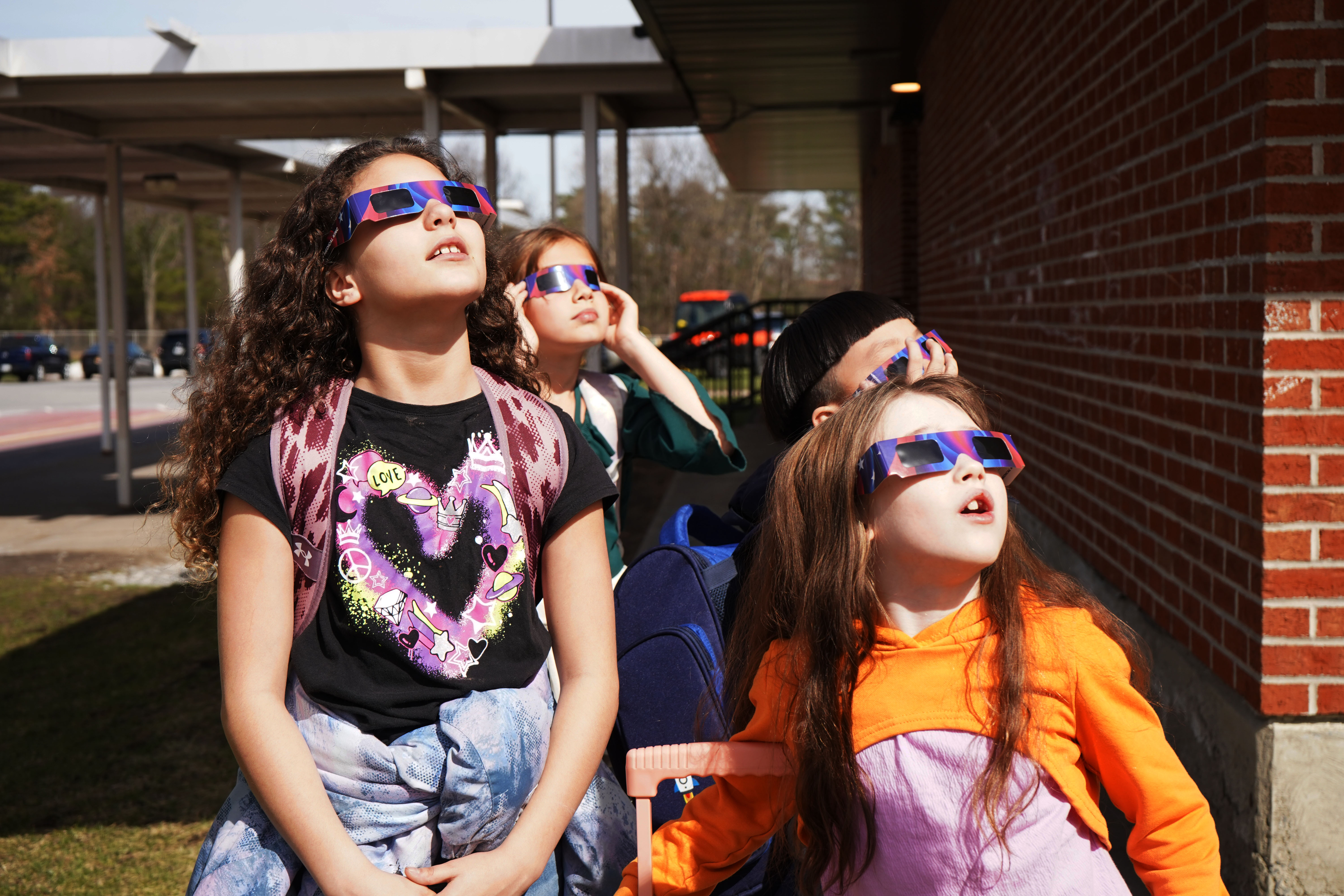 Kids look up at eclipse with protective glasses on. 