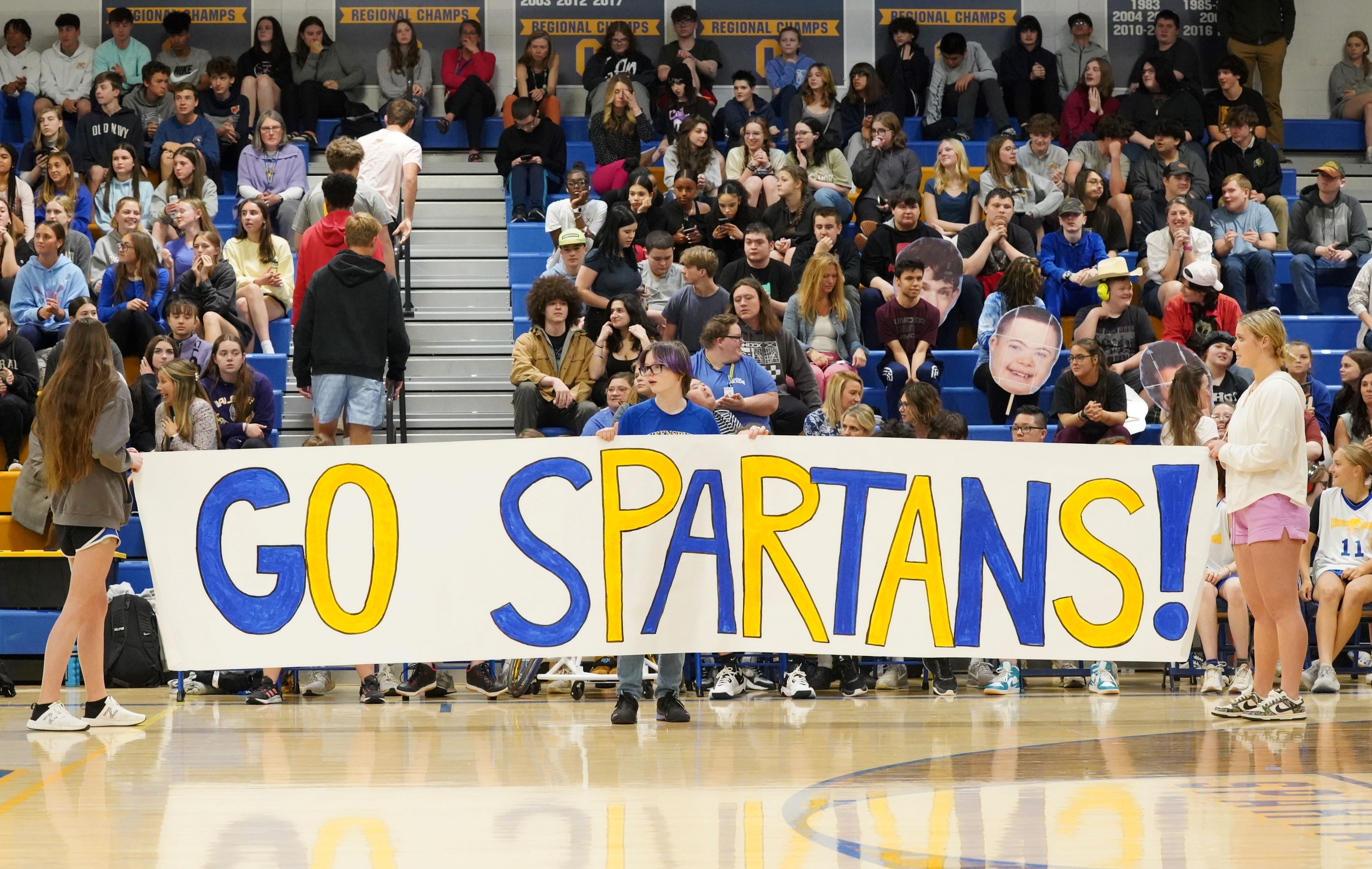 Students hold up sign at basketball game.