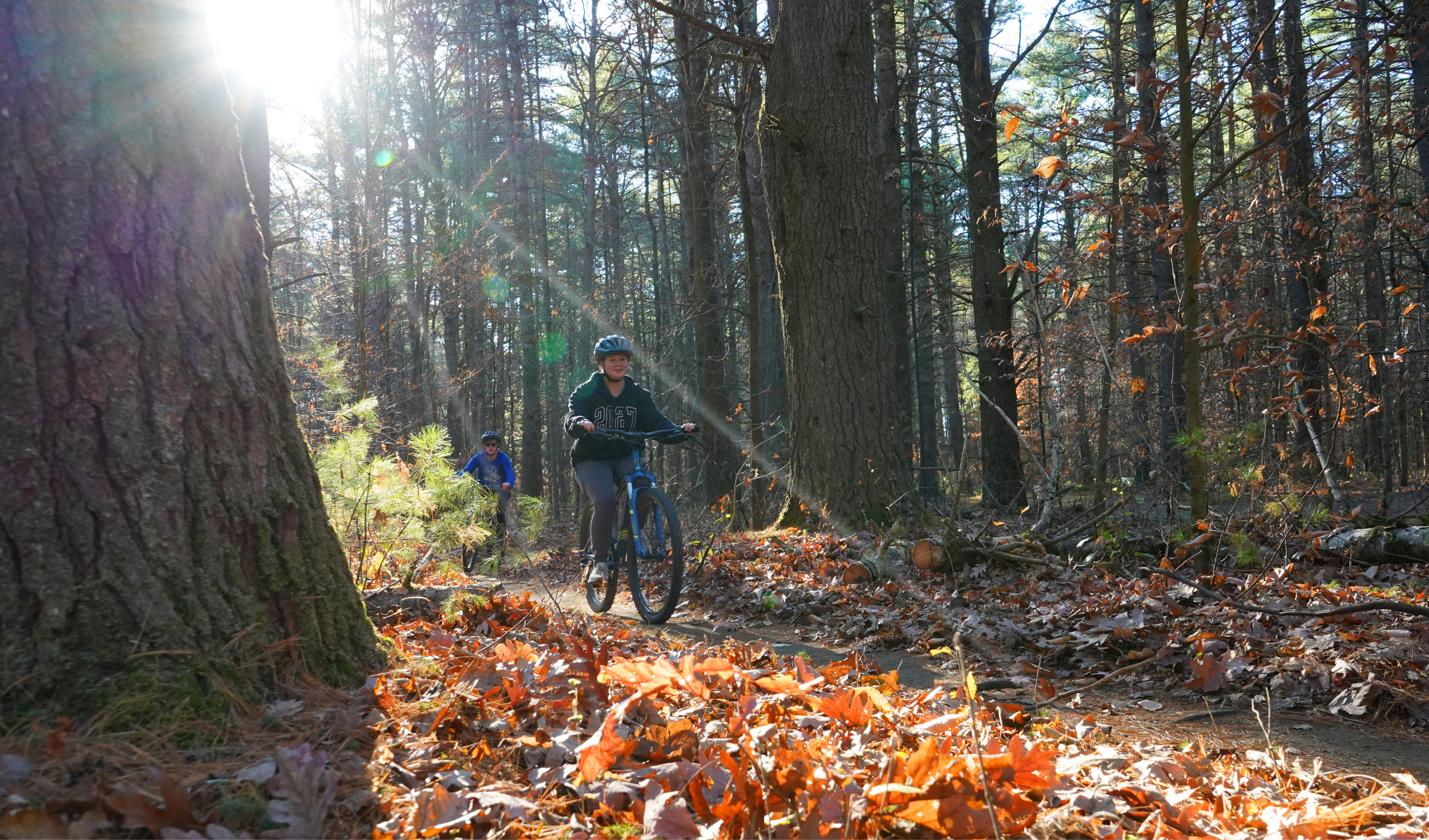 Students ride mountain bikes on trails behind school during fall. 