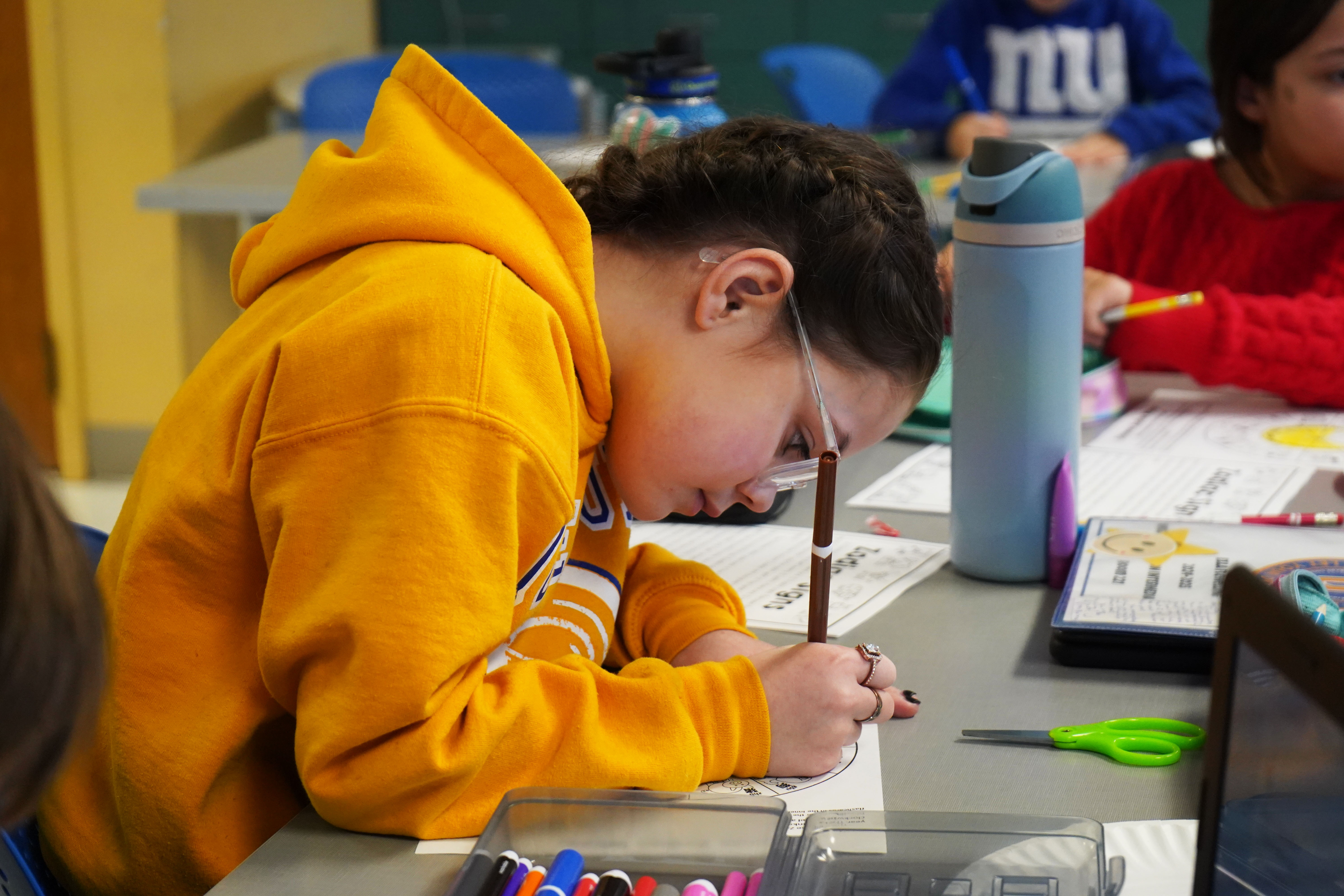 Student works on schoolwork at desk. 