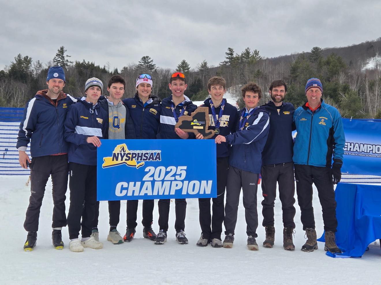 Nordic ski team members hold state champs sign. 