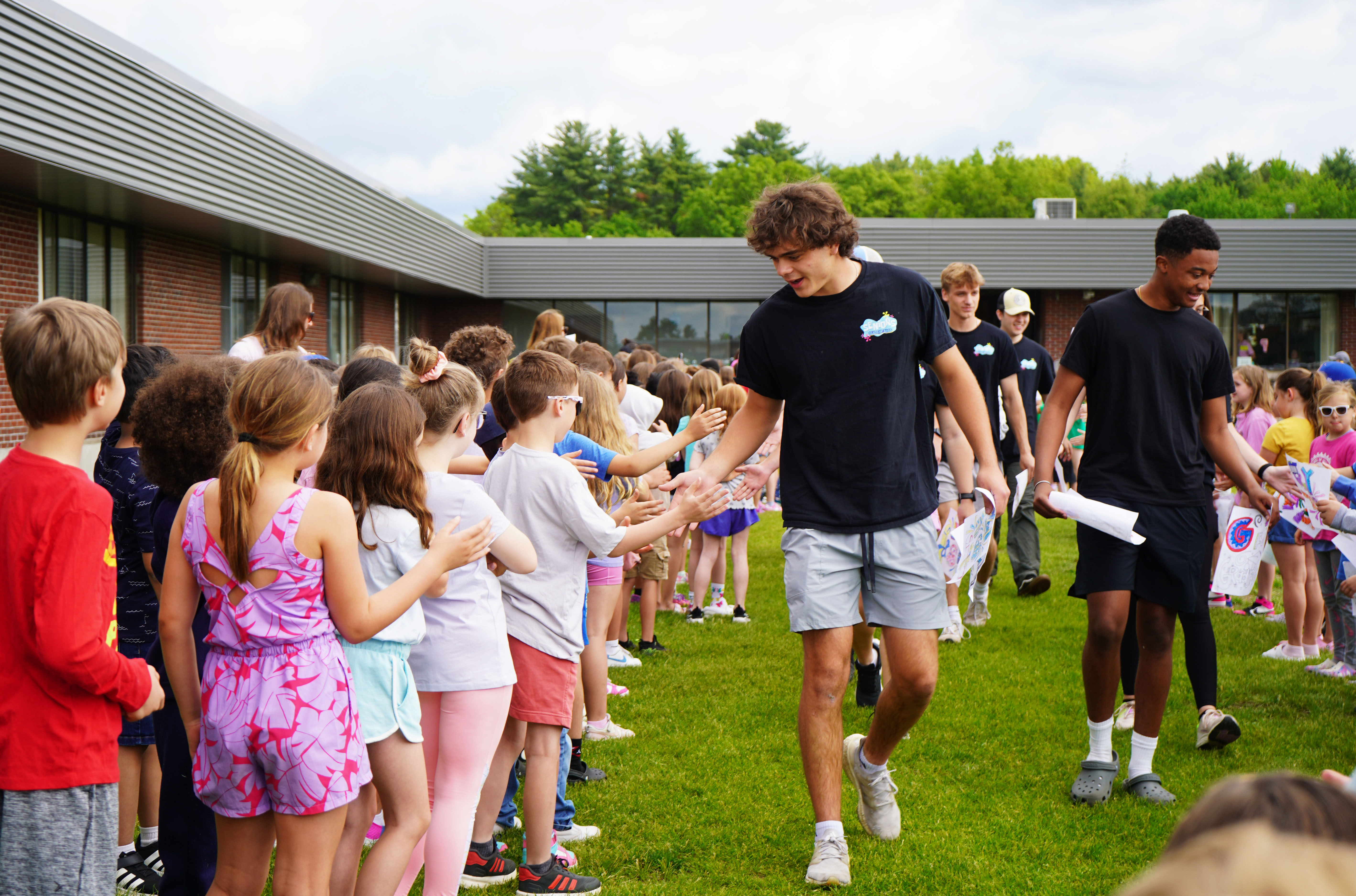 Senior walks through line of elementary students.