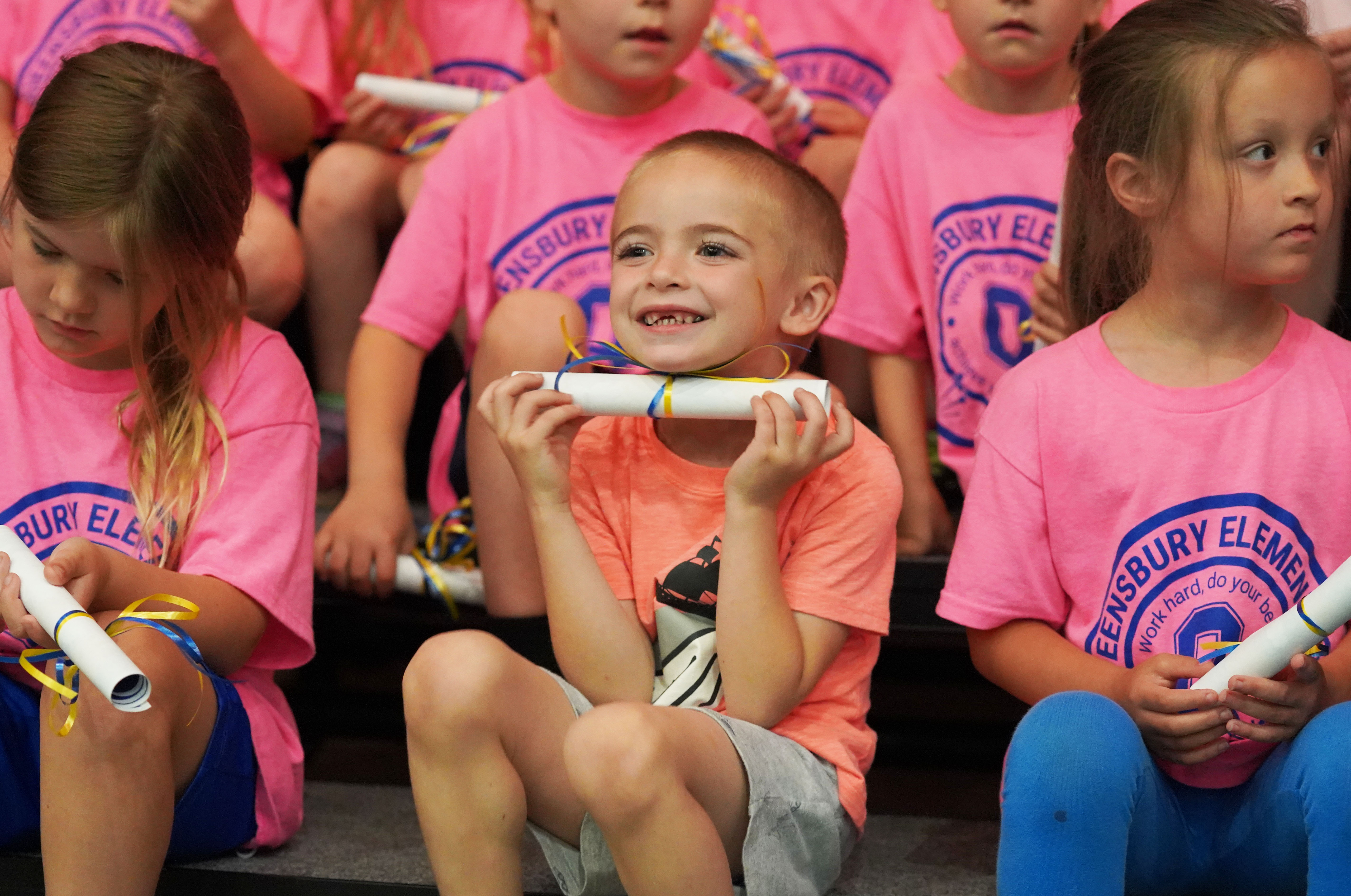 Student holds a rolled up diploma at Kindergarten Moving-up celebration.