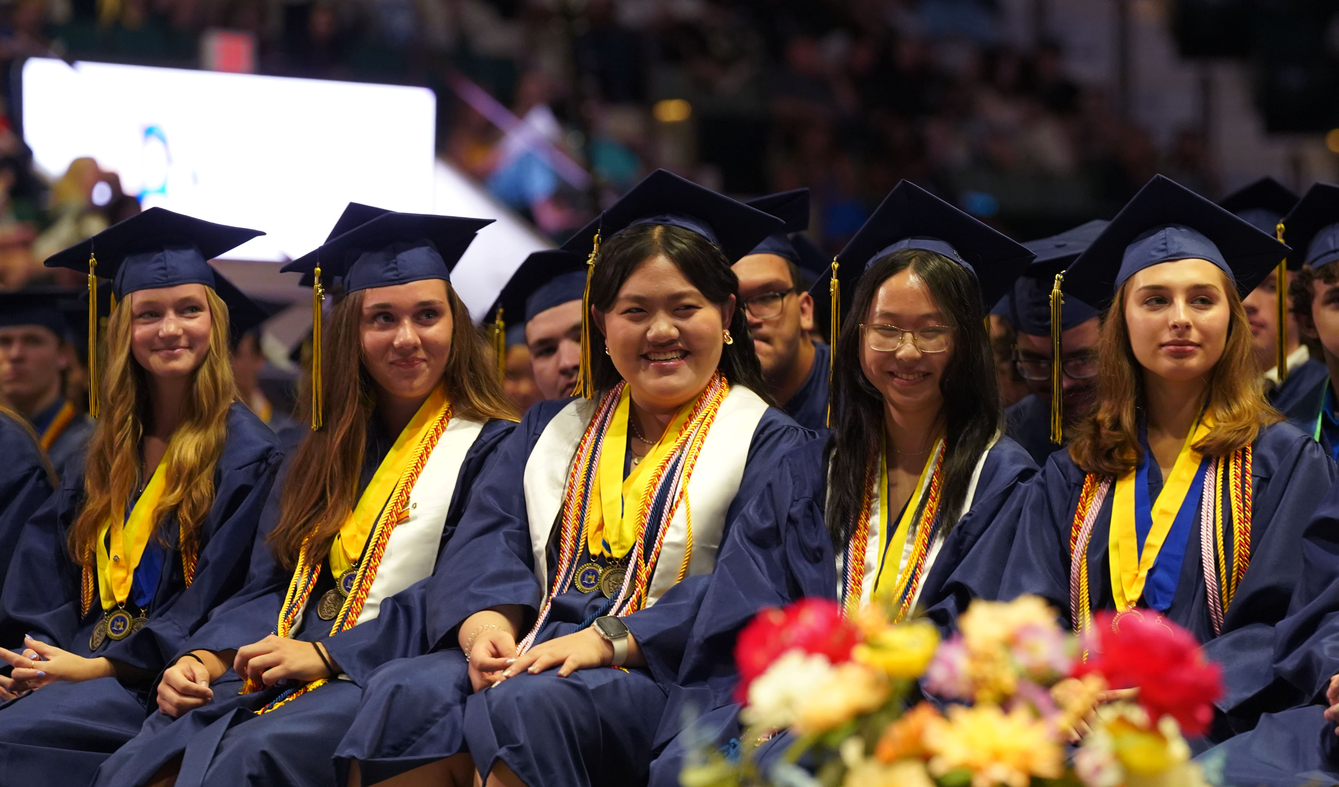 Students smile during graduation speech.