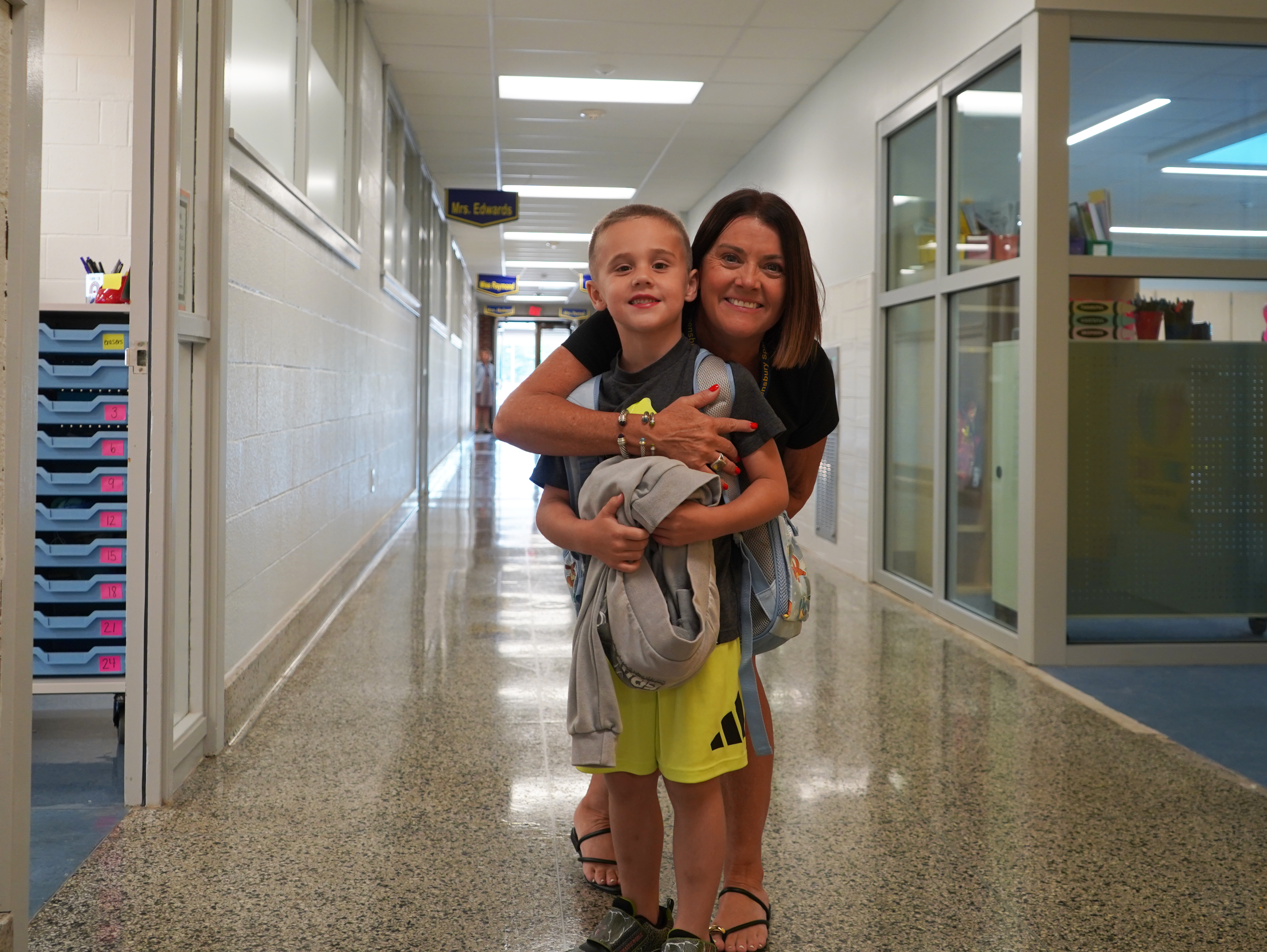 Student gets hug from teacher on first day of school.