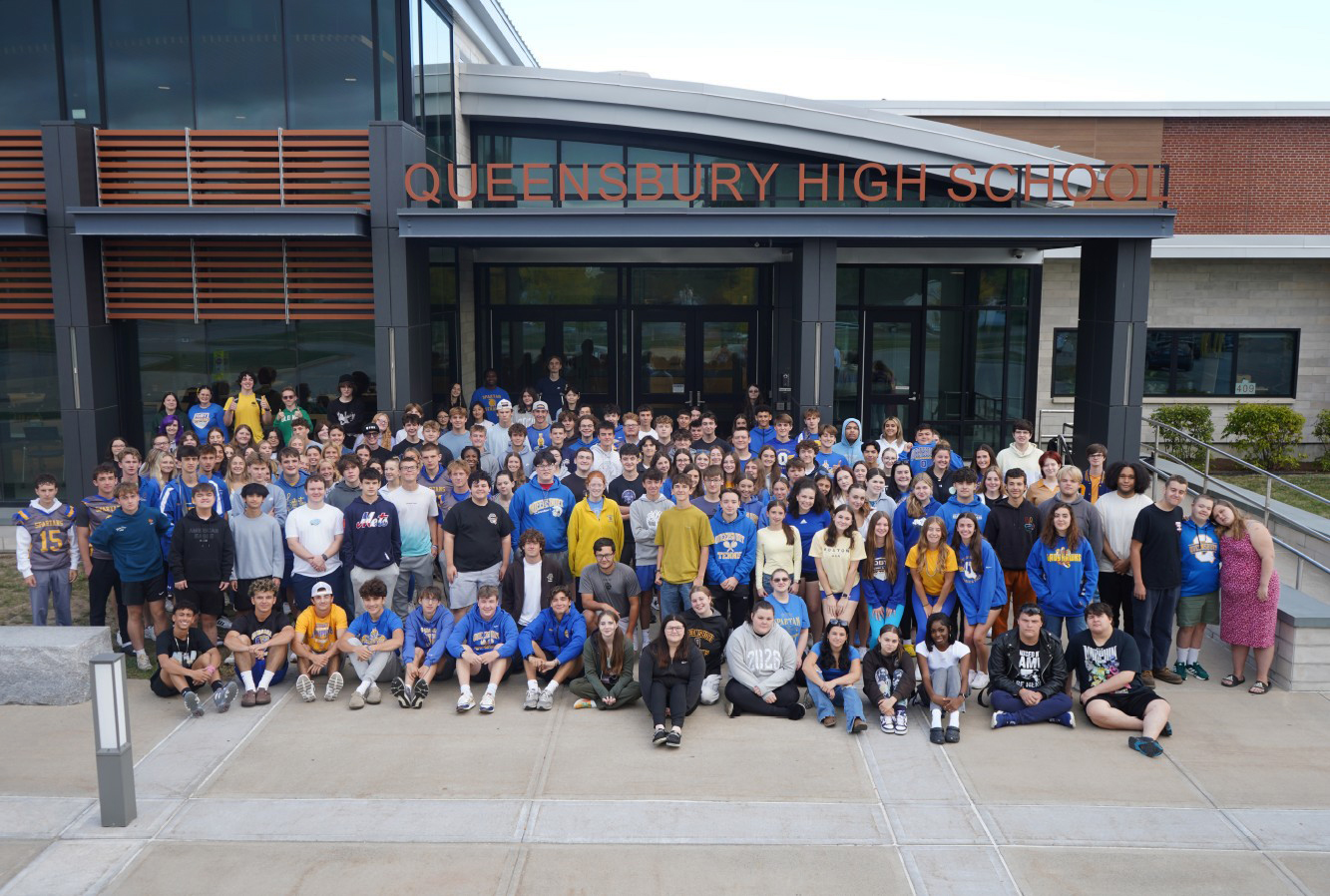 The senior Class of 2026 stands in front of school.