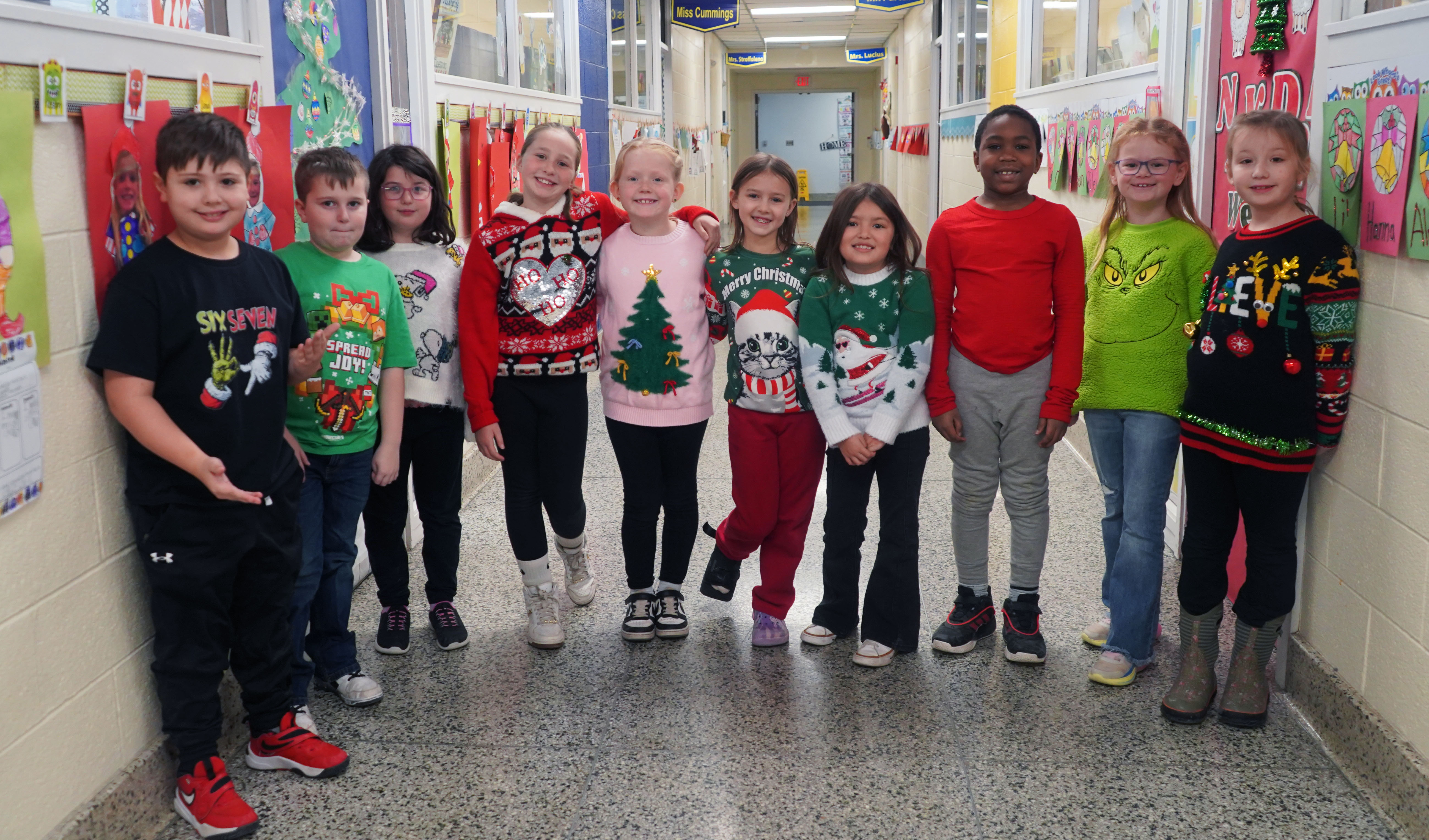 Students in holiday clothes stand in hallway at QES.