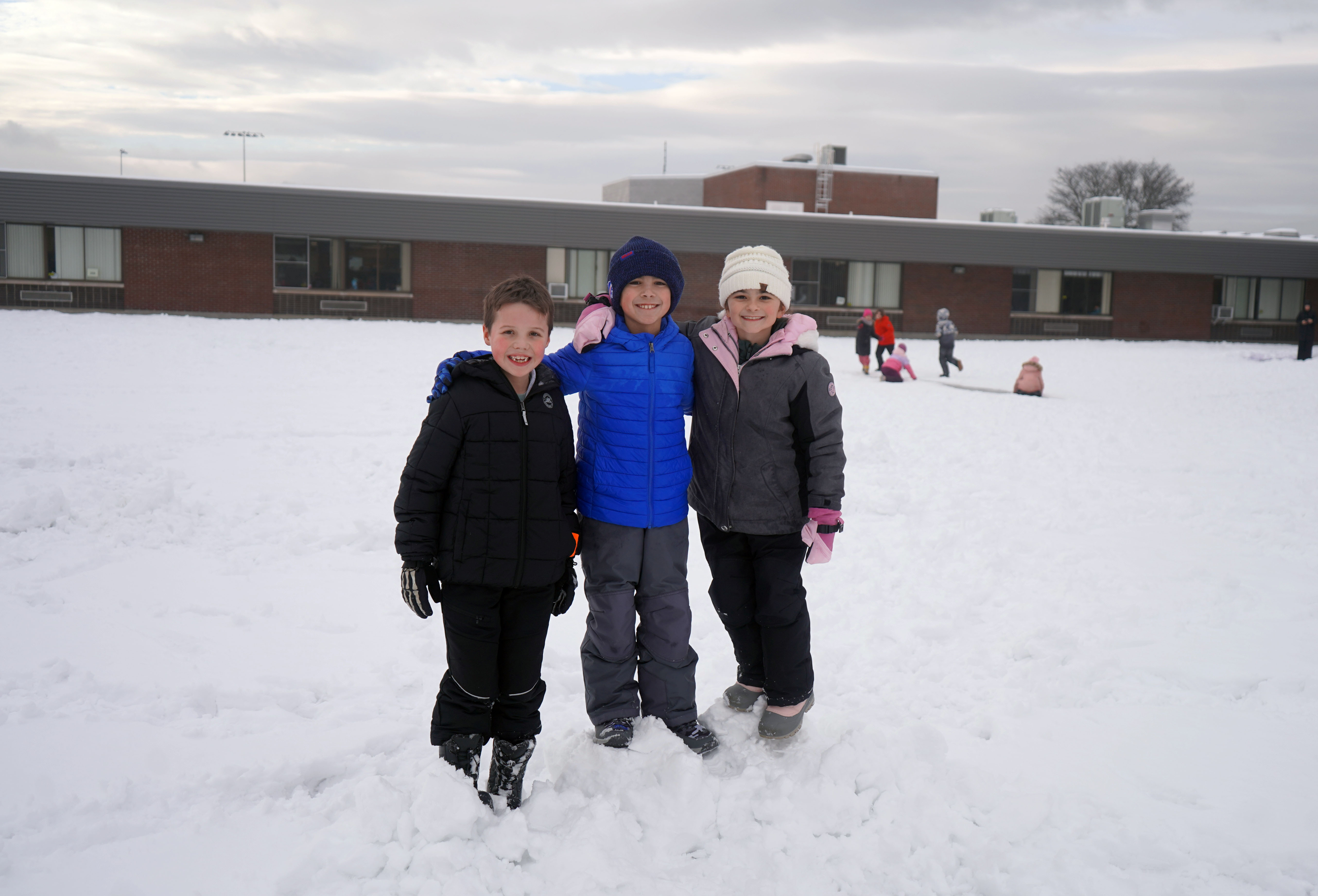 Three students play in the snow.