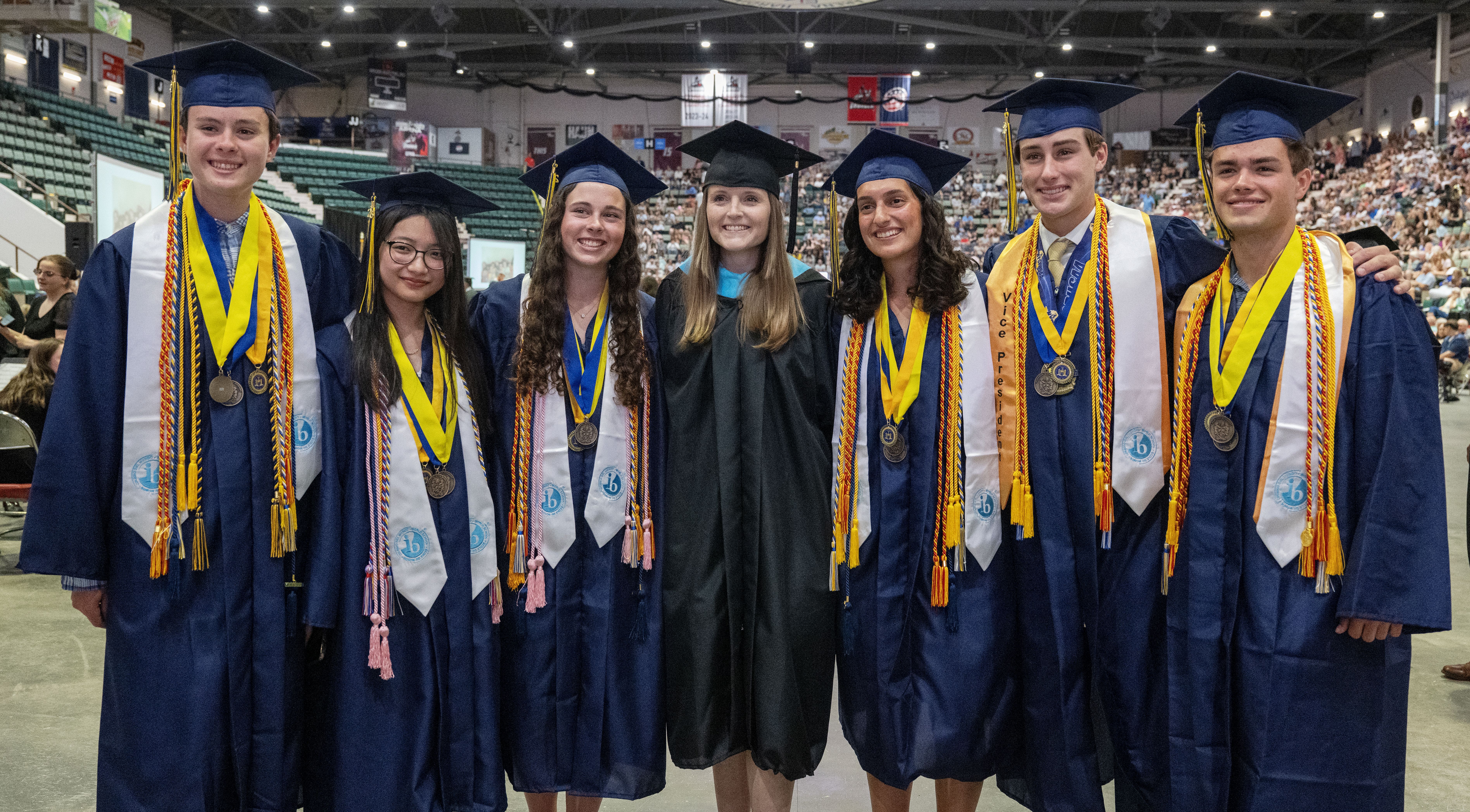 Students and teacher stand together at graduation.