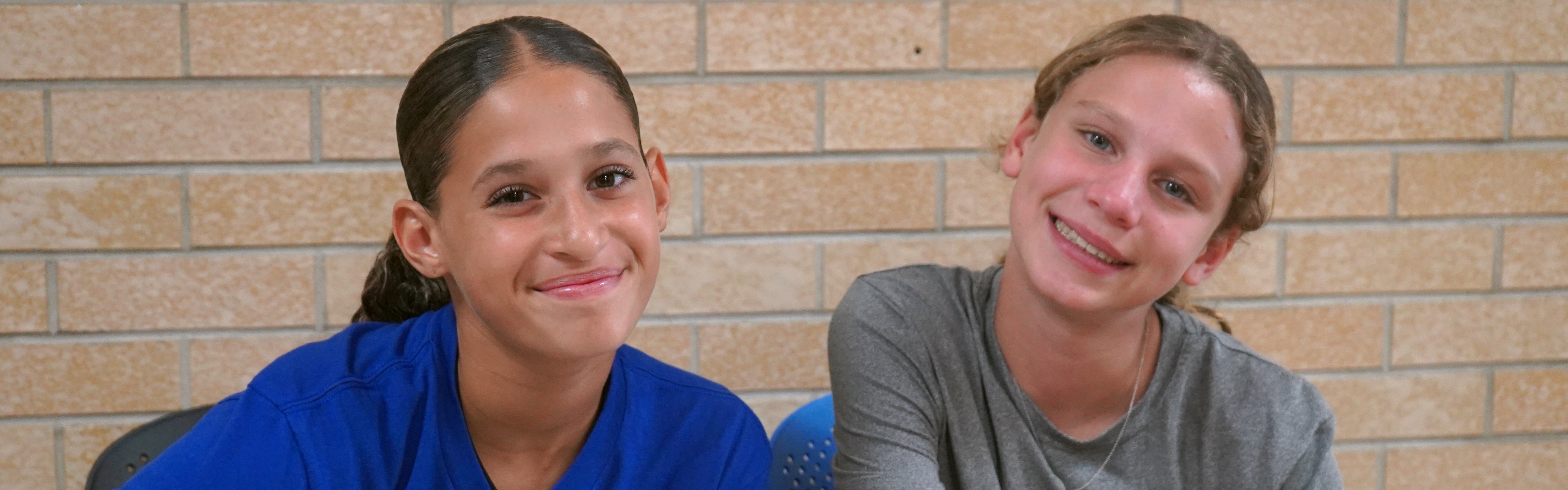 Two middle school students sit at desk in hallway.