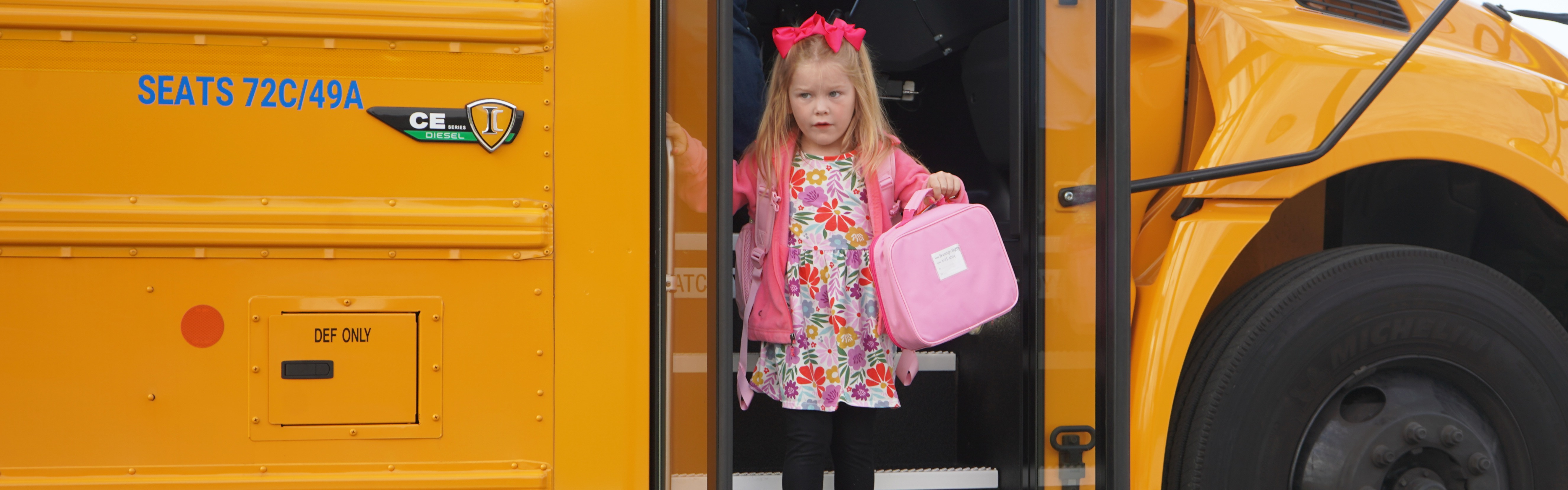 Young student steps off school bus on the first day of school.